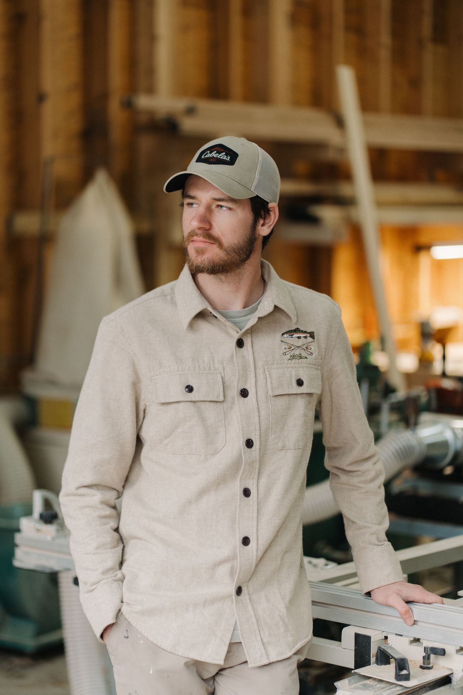 Craftsman in beige workwear and baseball cap working in a woodshop workshop.