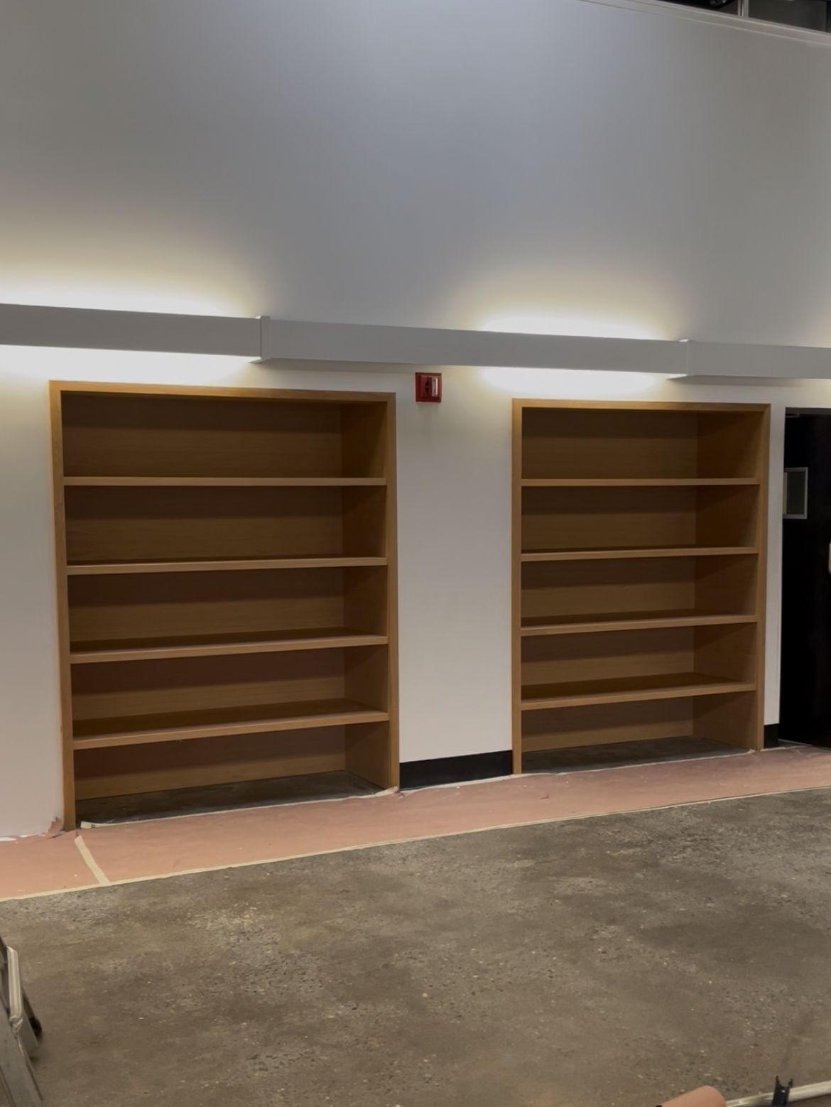 Long wall of empty wooden library shelves in commercial or institutional setting.
