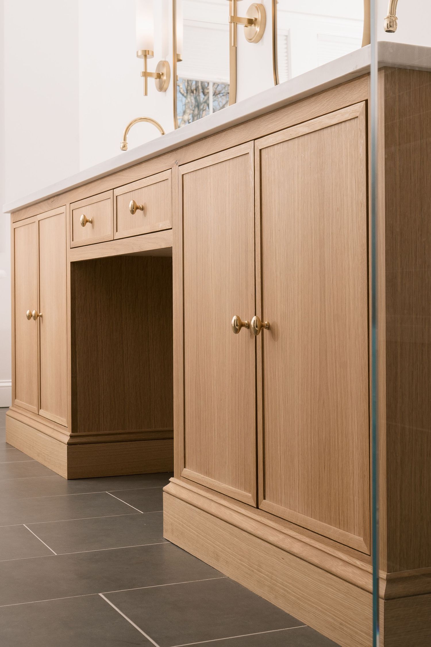 Light wood bathroom cabinet with brass hardware and built-in vanity space.
