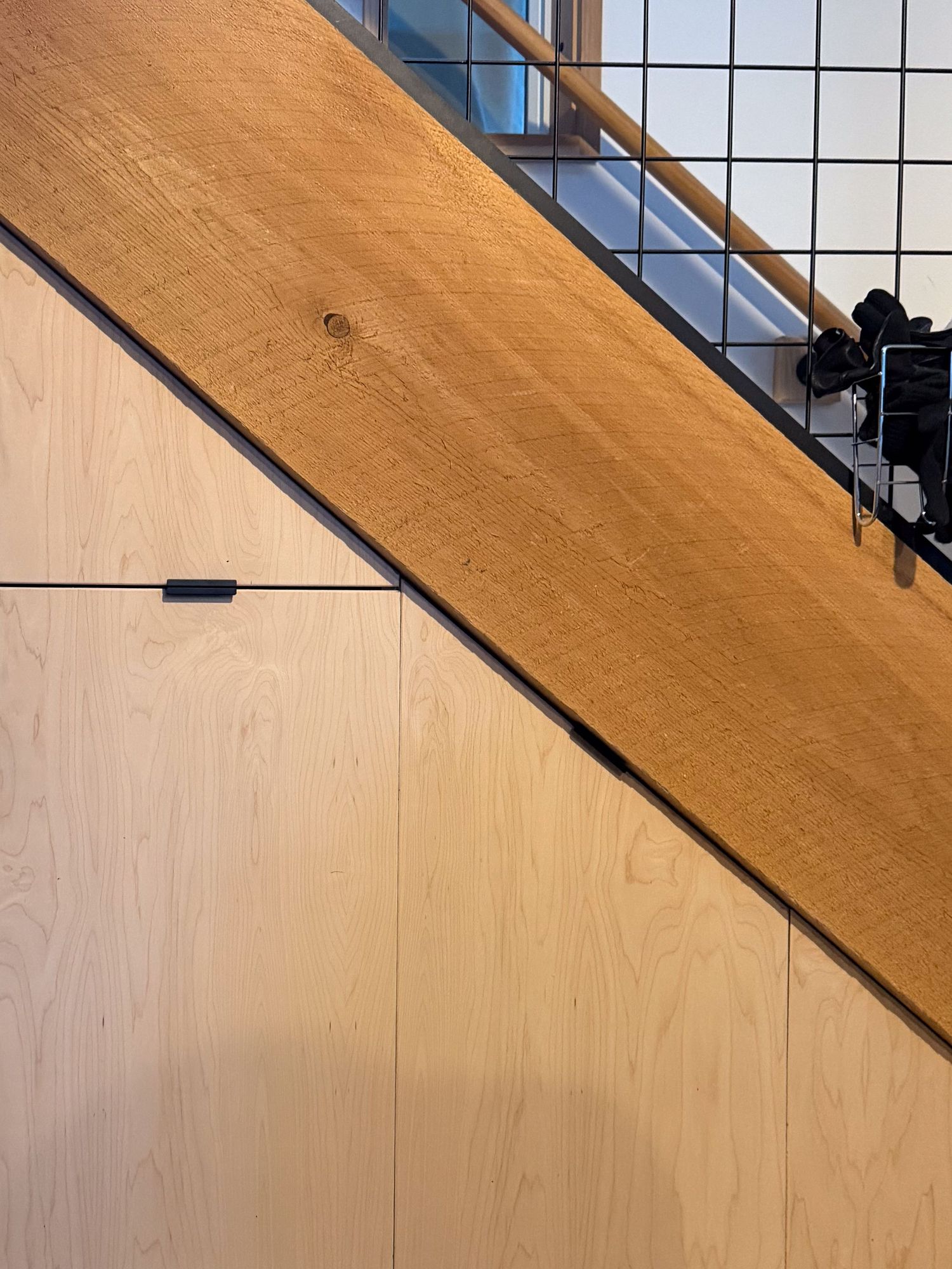 Angled view of staircase showing wooden beam and glass panel installation details.