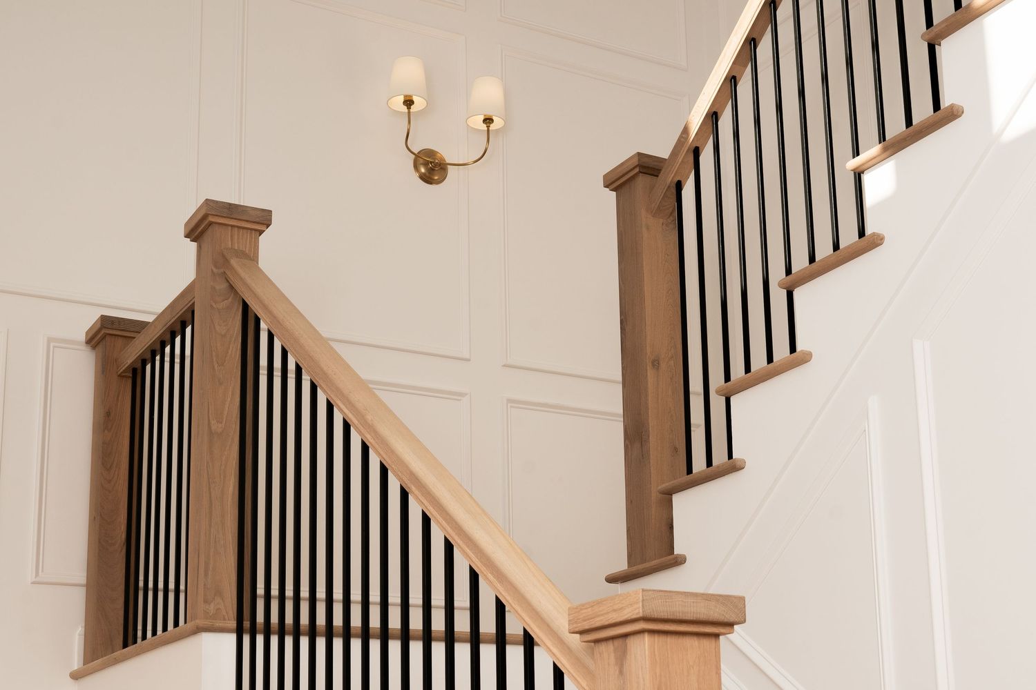 Elegant white staircase with dark wood railings and beige carpet runner in a modern home interior.