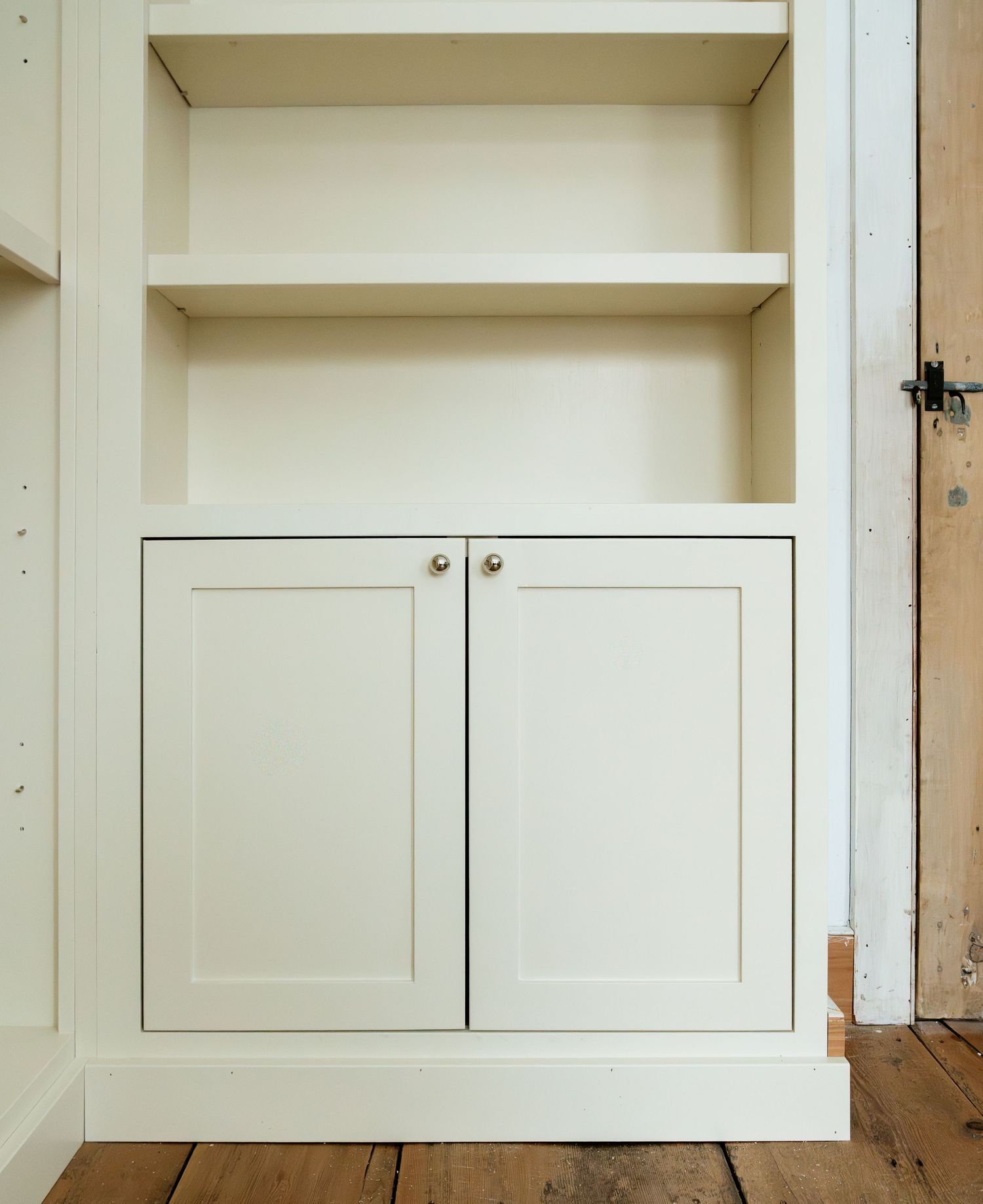Built-in white cabinet with double doors and shelving above.