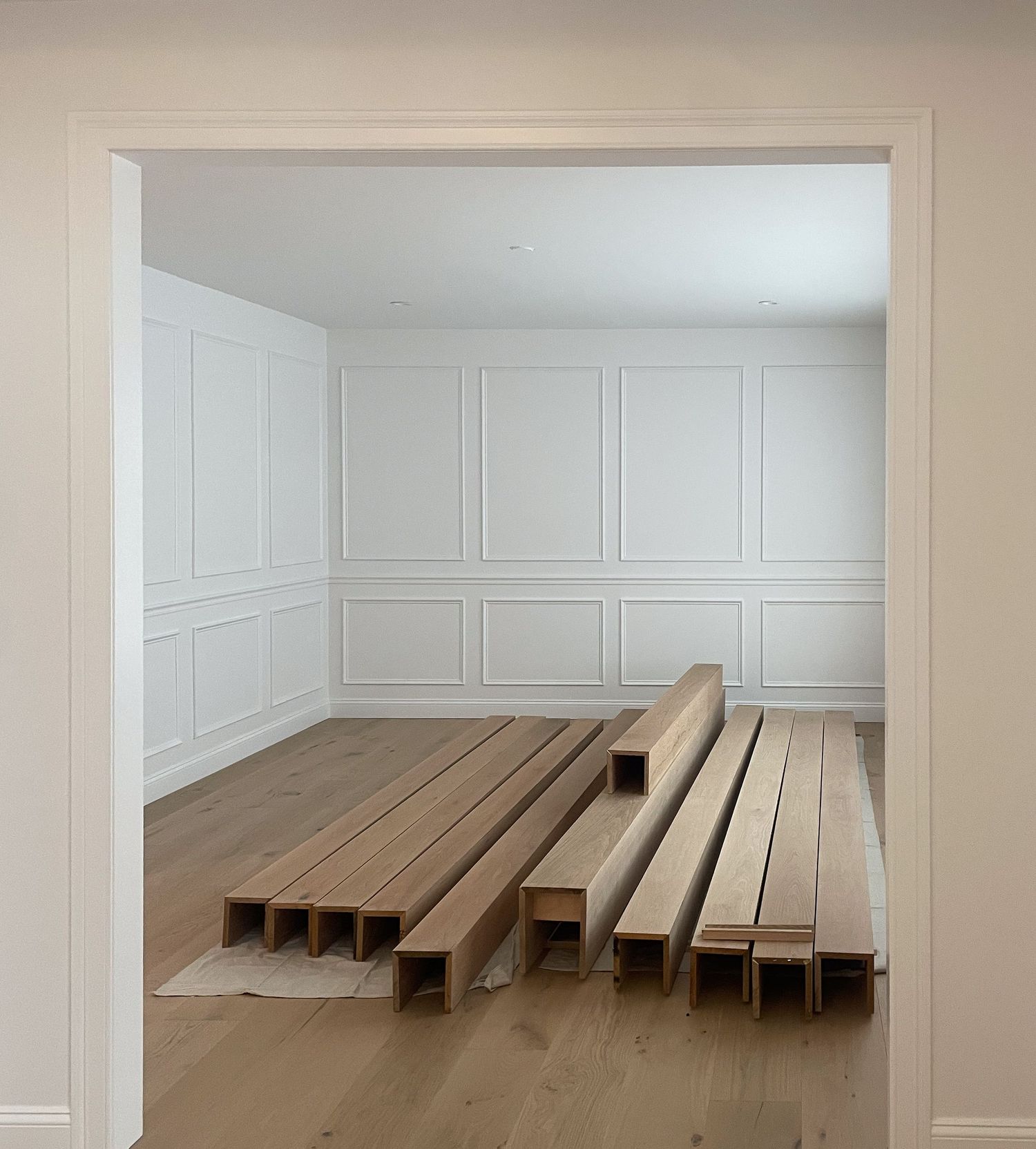Stacks of wooden boards and construction materials laid out on a light hardwood floor.