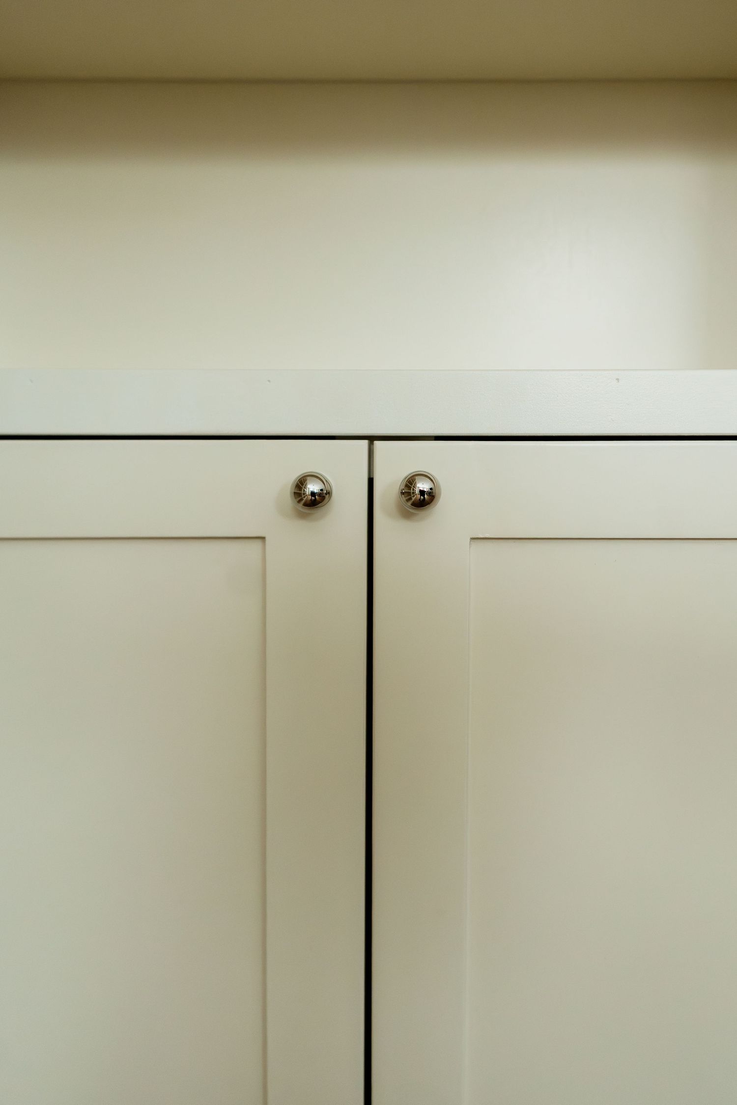 Close-up detail of white cabinet doors with brass knobs showing clean modern design.