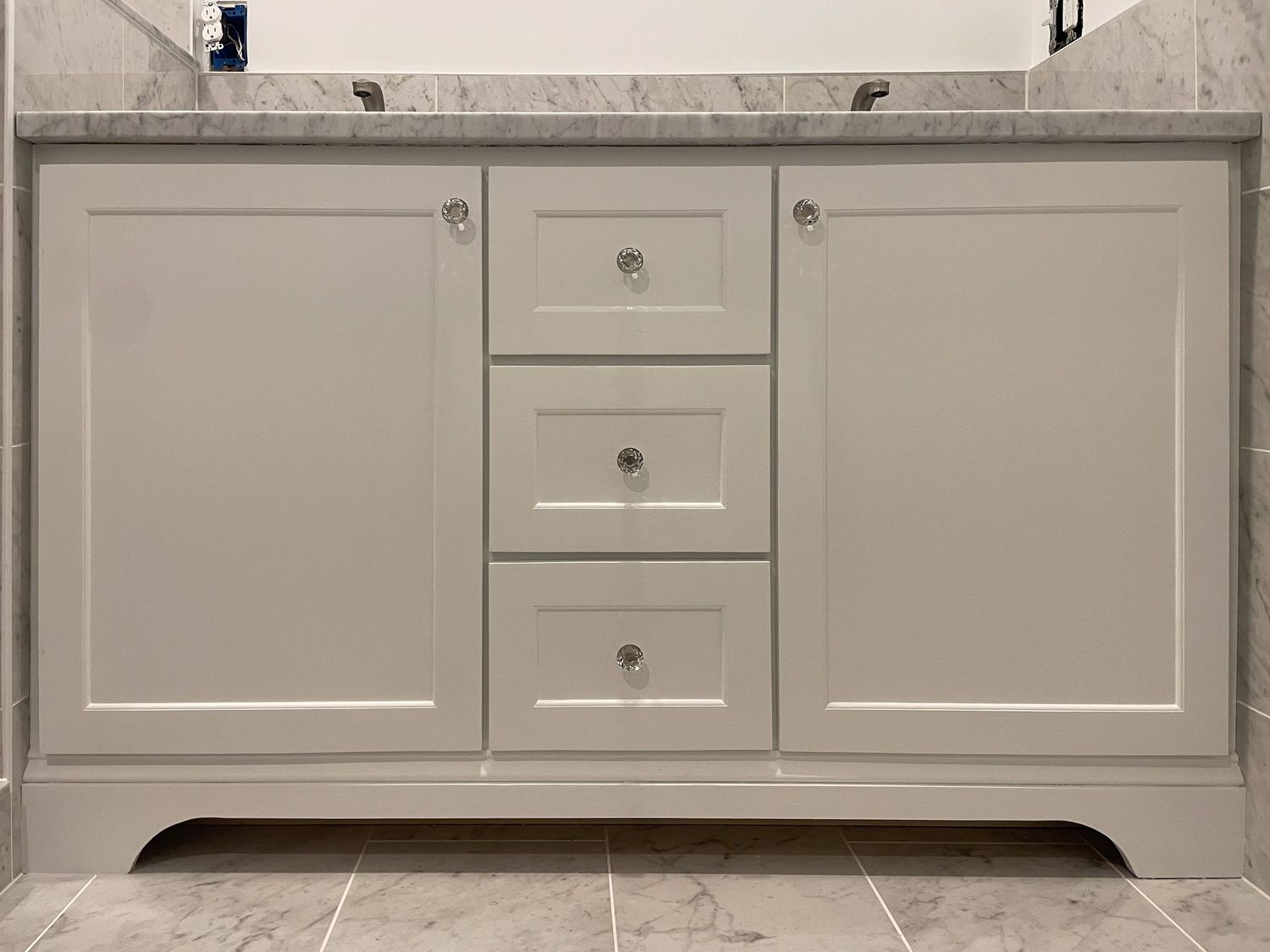 Light gray kitchen base cabinets with marble countertops and clean modern hardware.