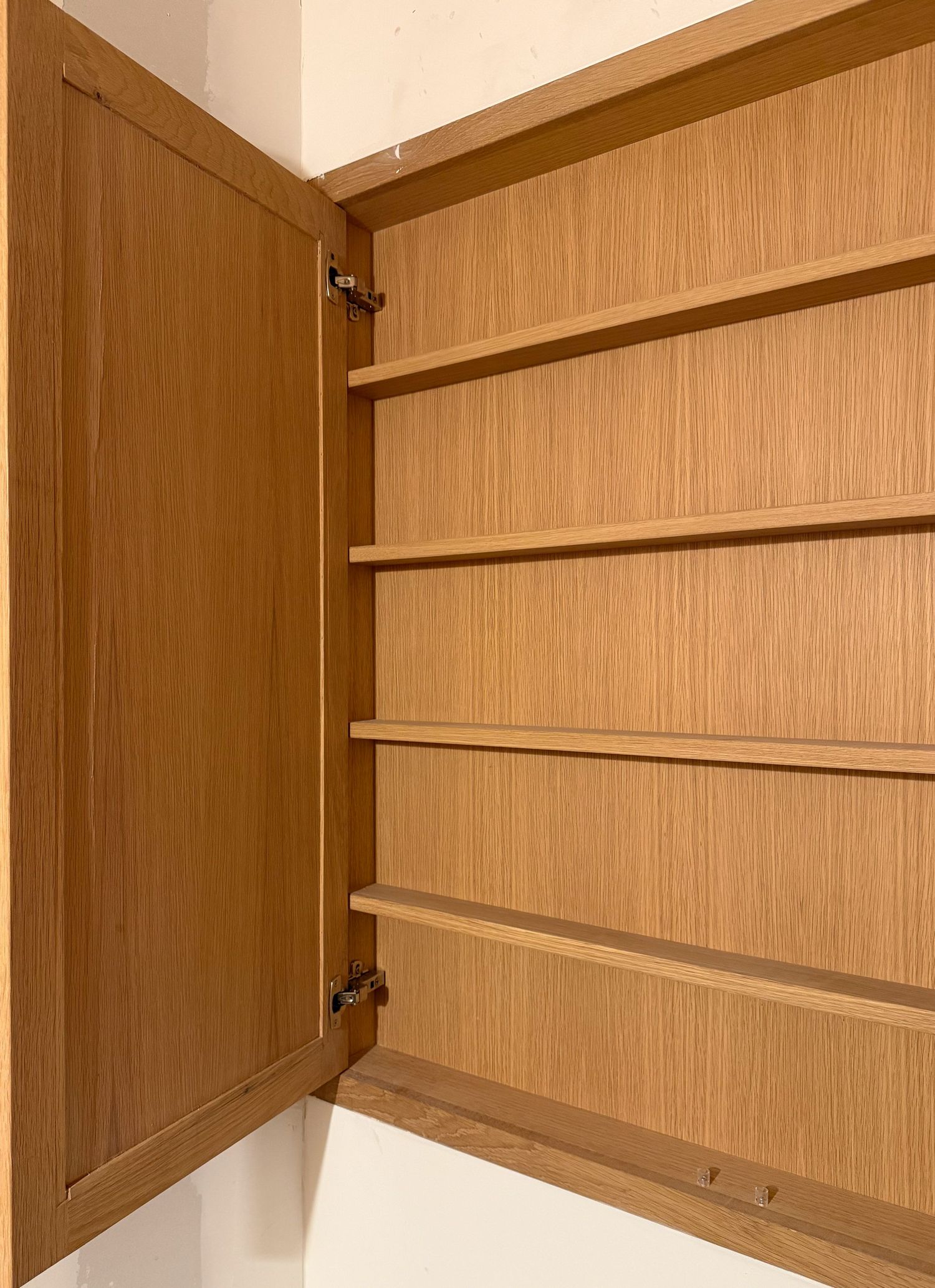 Built-in wooden storage cabinet with adjustable shelving rails and hinged doors.