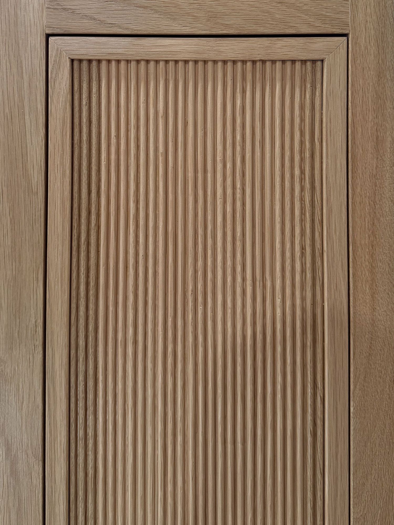 Close-up of vertical wooden slats creating a ribbed pattern texture on cabinet door.