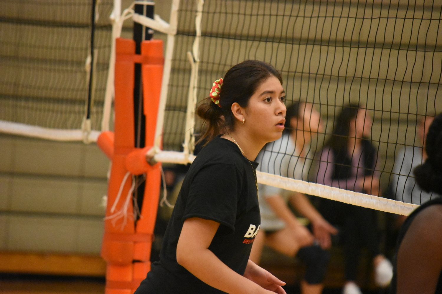 Indoor volleyball practice with players working on serving techniques.
