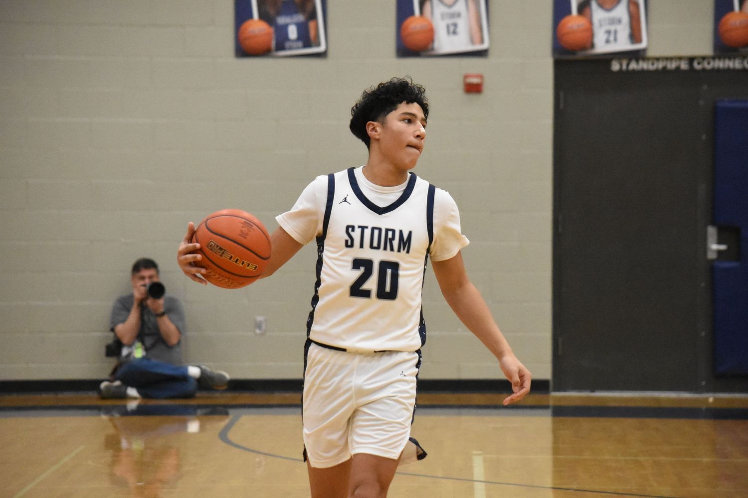 Player in white Storm jersey makes offensive move during basketball game.