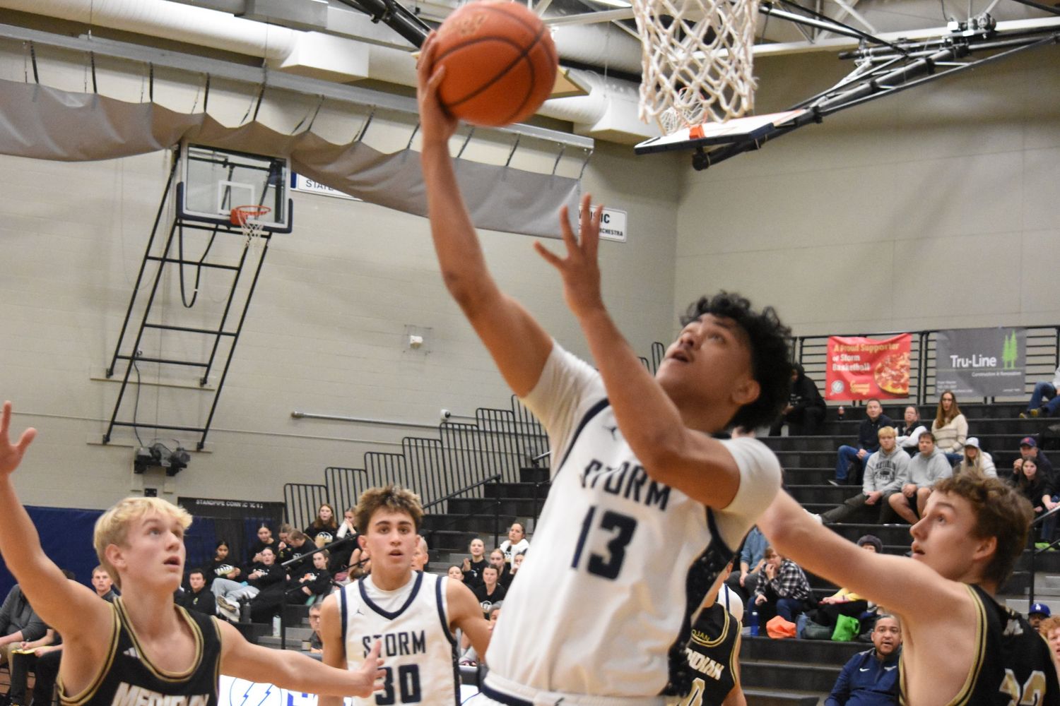 Player in Storm jersey 13 goes for layup while surrounded by defenders during basketball game.