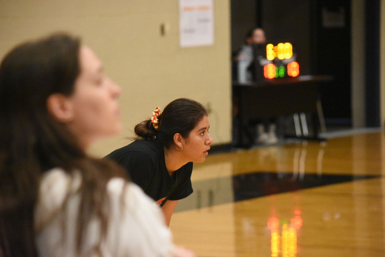Basketball players practicing defensive positions during team training in gymnasium.