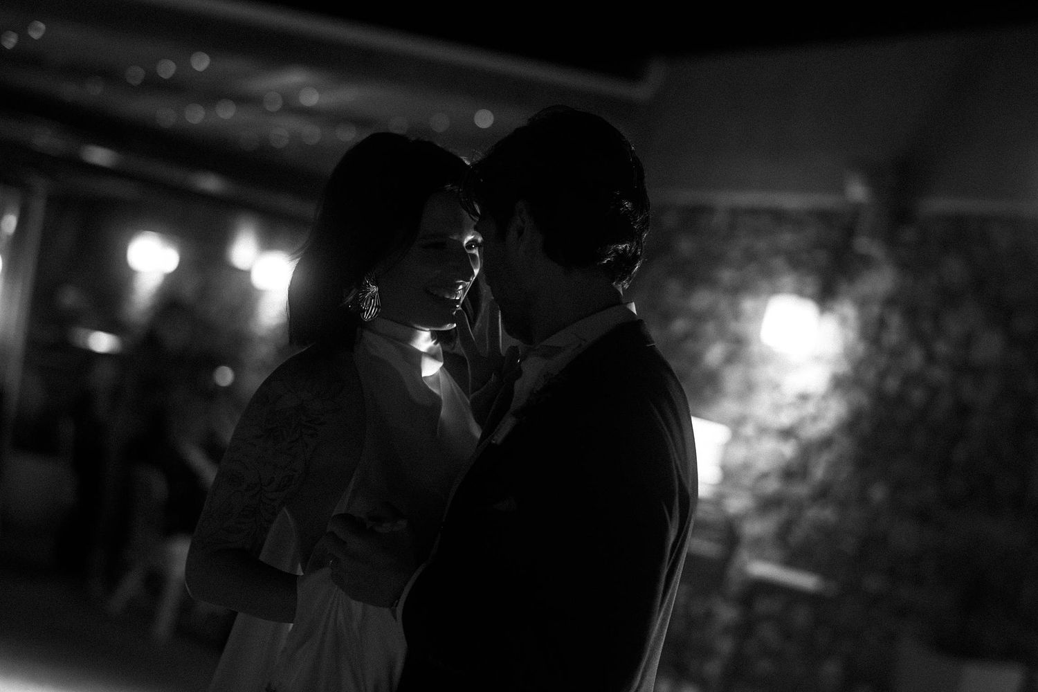 A romantic silhouette of a couple sharing an intimate moment on a dance floor with soft lighting in the background.