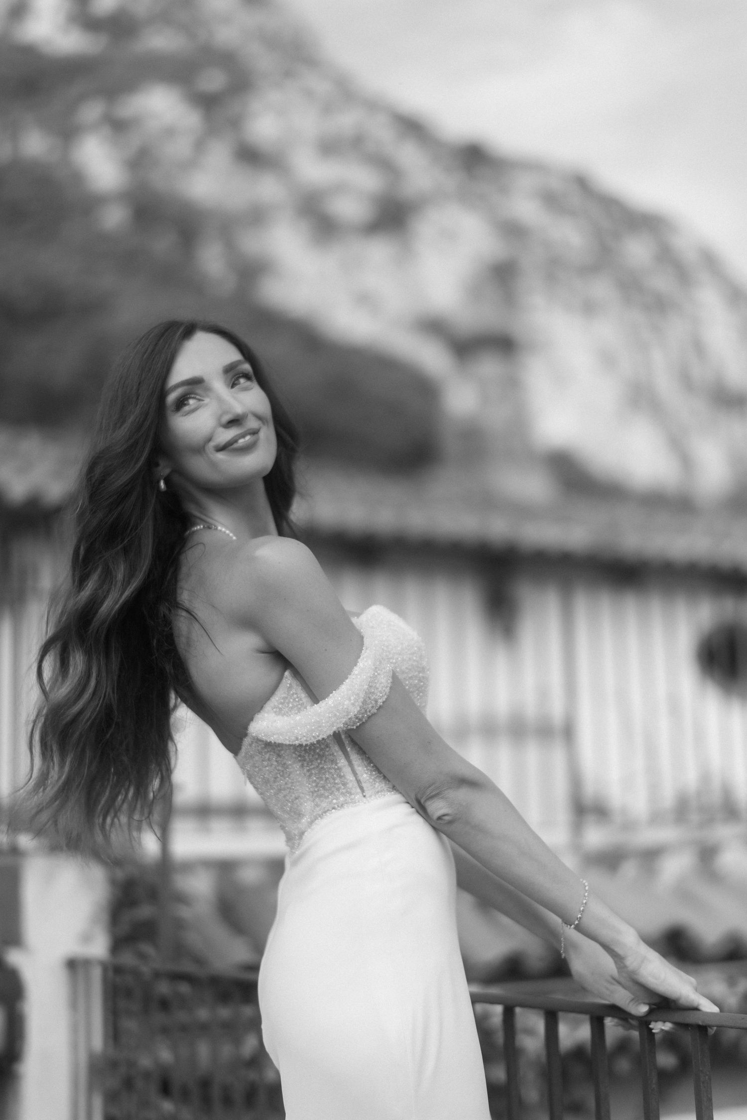 A woman in a white dress poses outdoors in a black and white photo series showing joyful movement and expression.