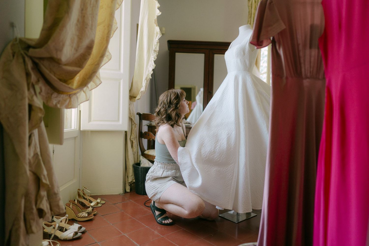 A series of wedding dress detail shots showing flowing white fabric against pink curtains and wooden floors.