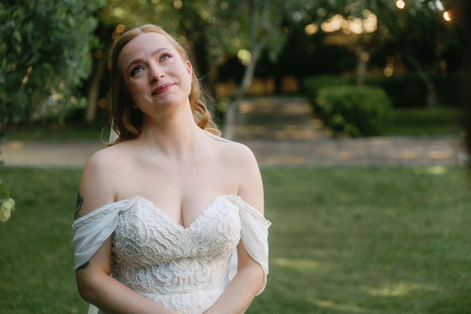 Elegant off-shoulder wedding dress details shown in natural outdoor lighting.