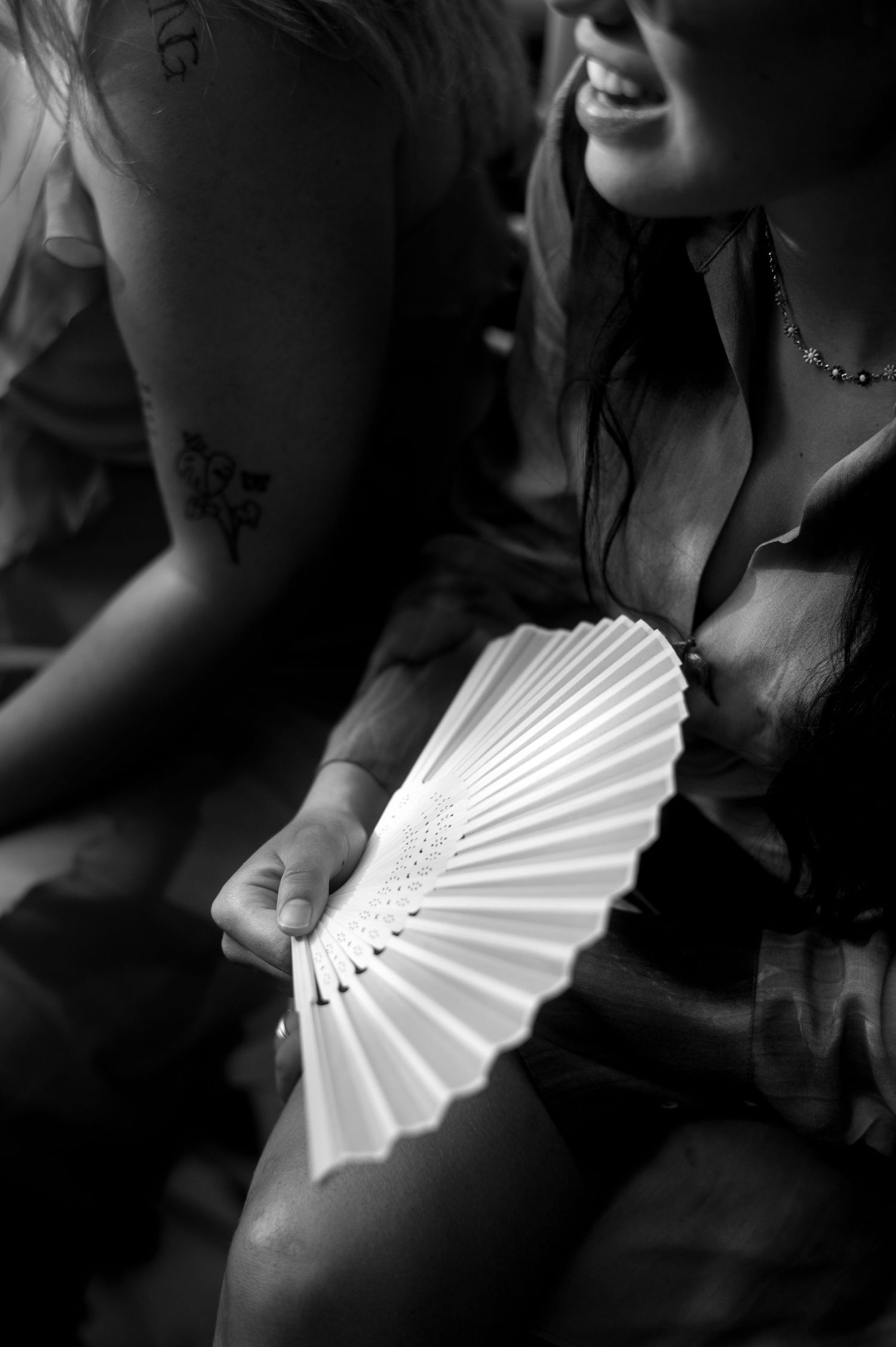 A series of black and white photos showing a white folding fan being held against dark clothing.