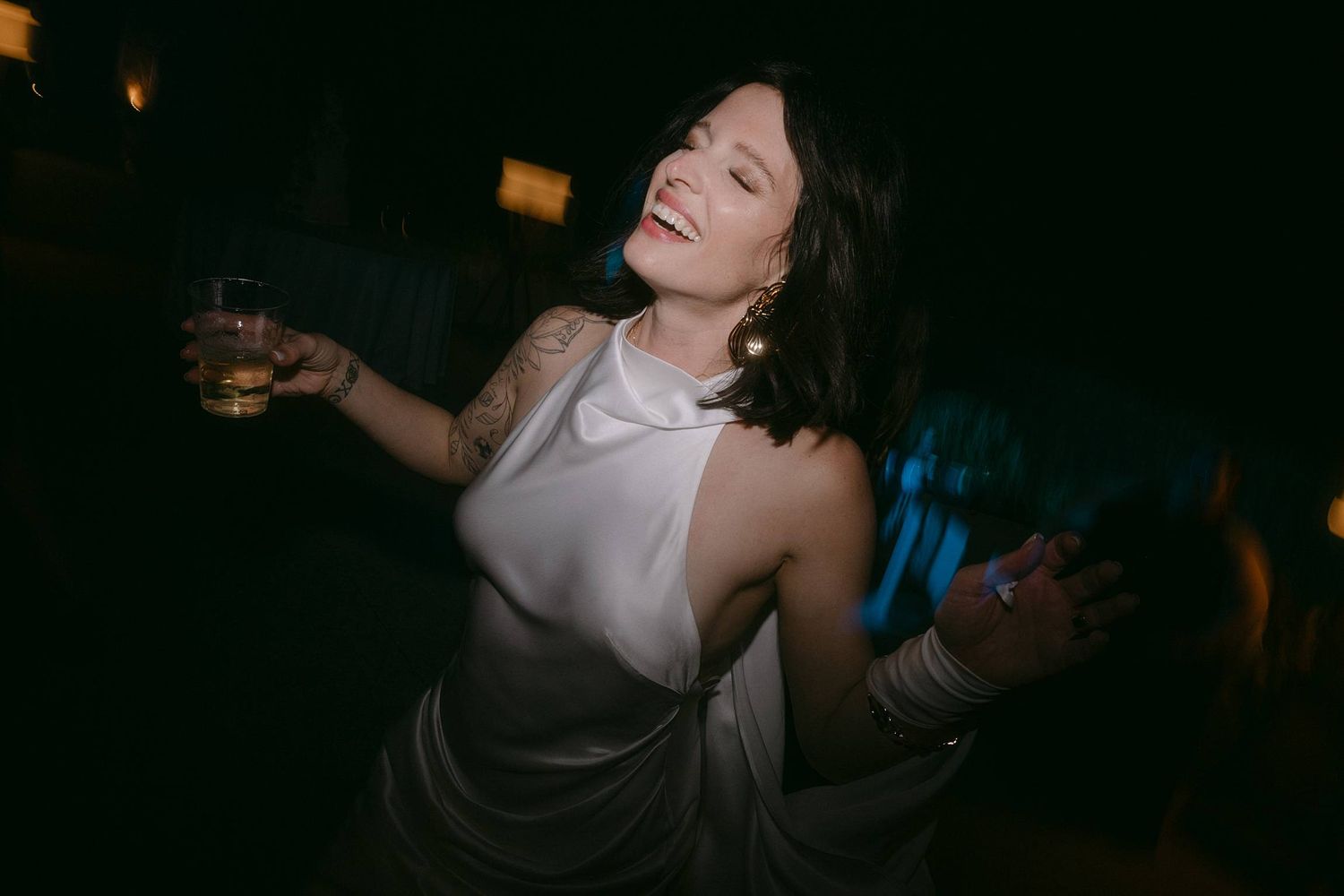 A person in a white top dances energetically in a dark nightclub setting with atmospheric lighting.