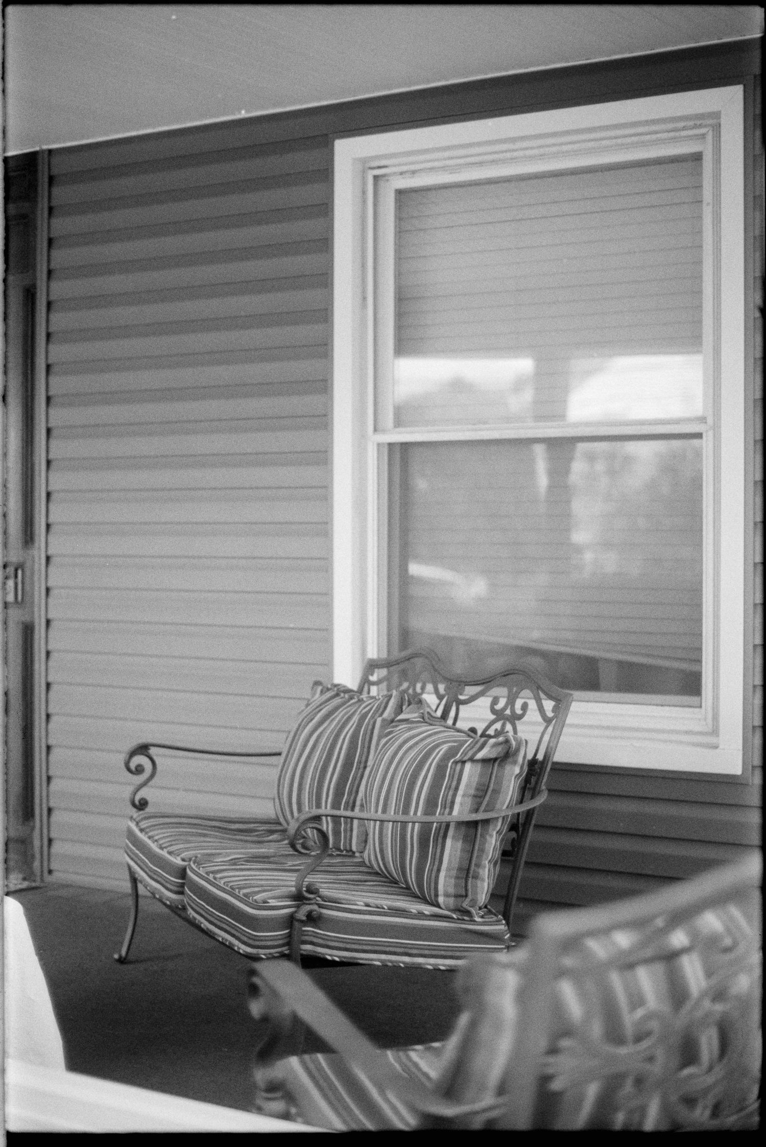 A series of four black and white photographs showing a patio bench with striped cushions against a house exterior.