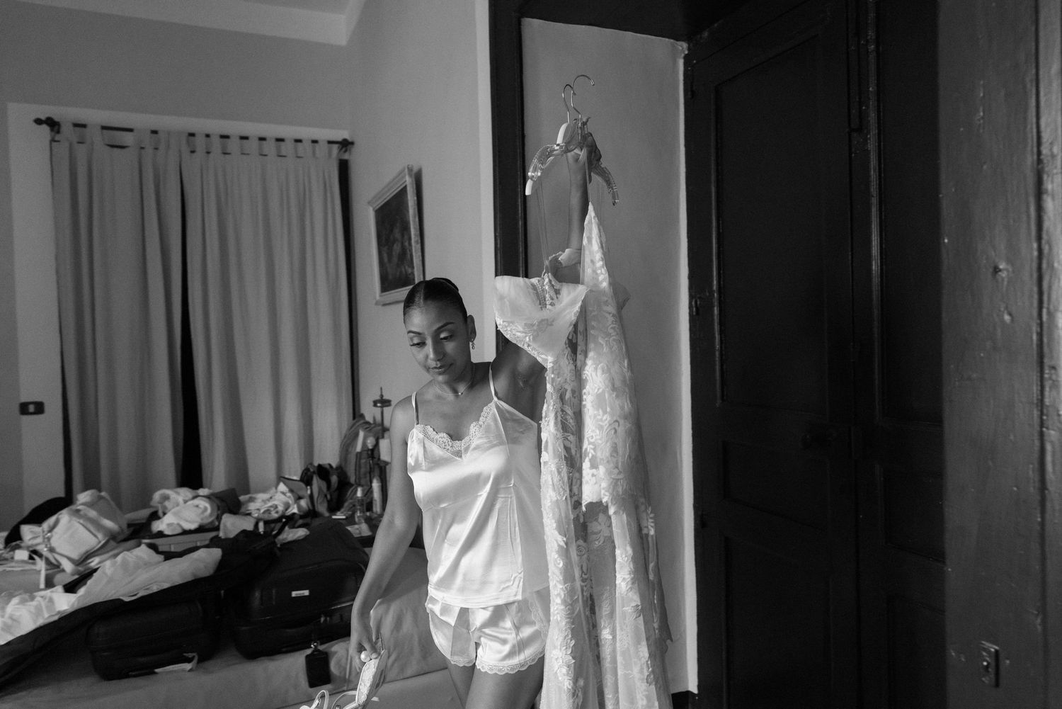 A black and white photograph shows a figure in white medical protective gear standing in a hospital hallway.