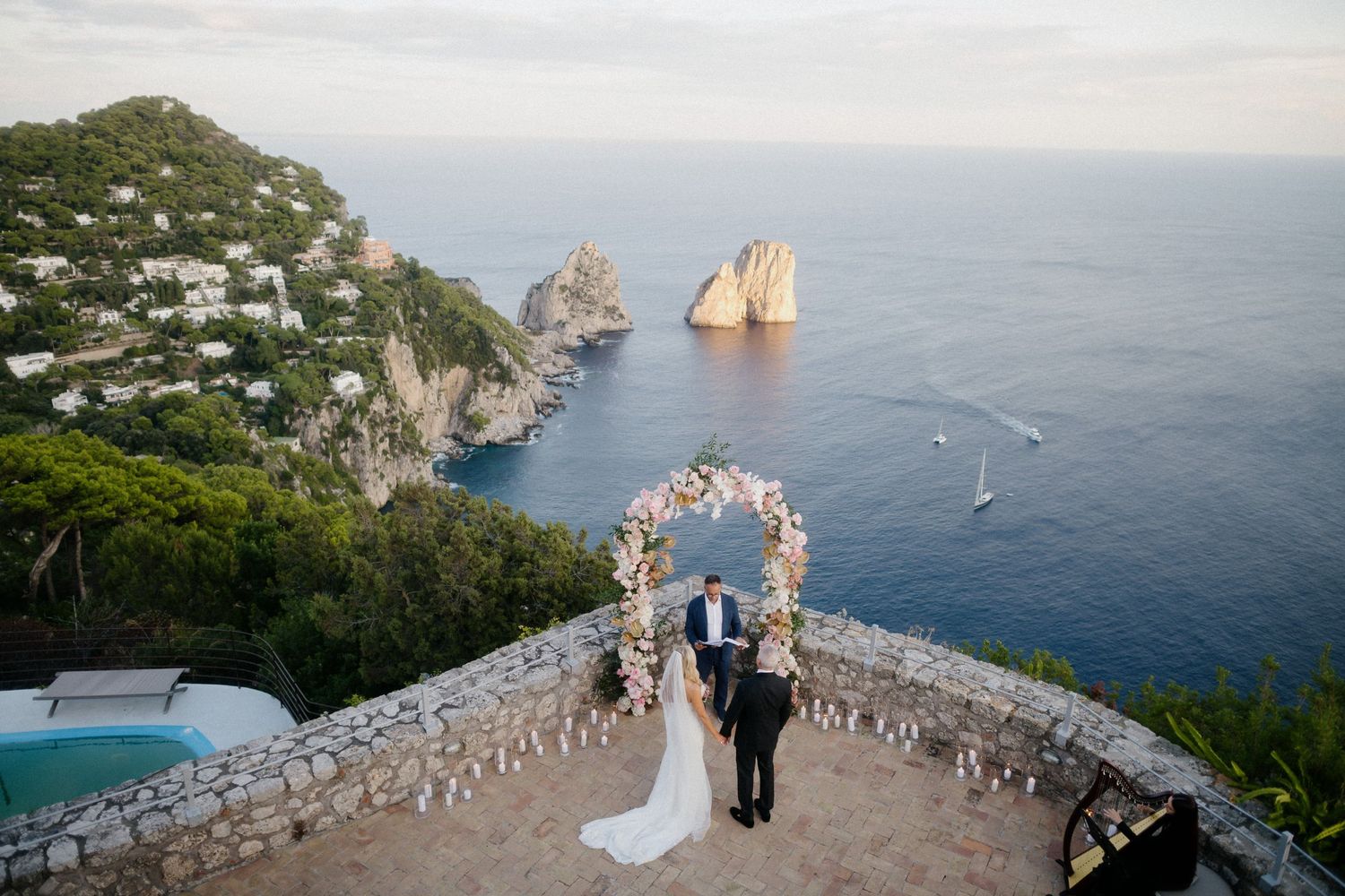 Scenic wedding ceremony overlooking the Faraglioni rocks and Mediterranean Sea from a luxury terrace on Capri Island.