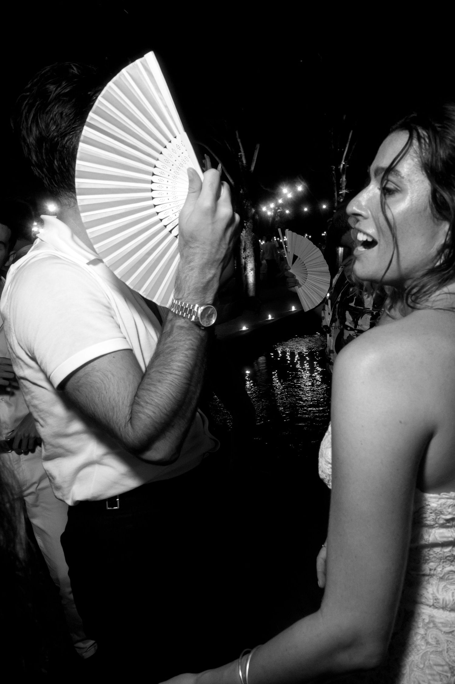Black and white photo series of dancers using decorative white hand fans at a nightclub party.