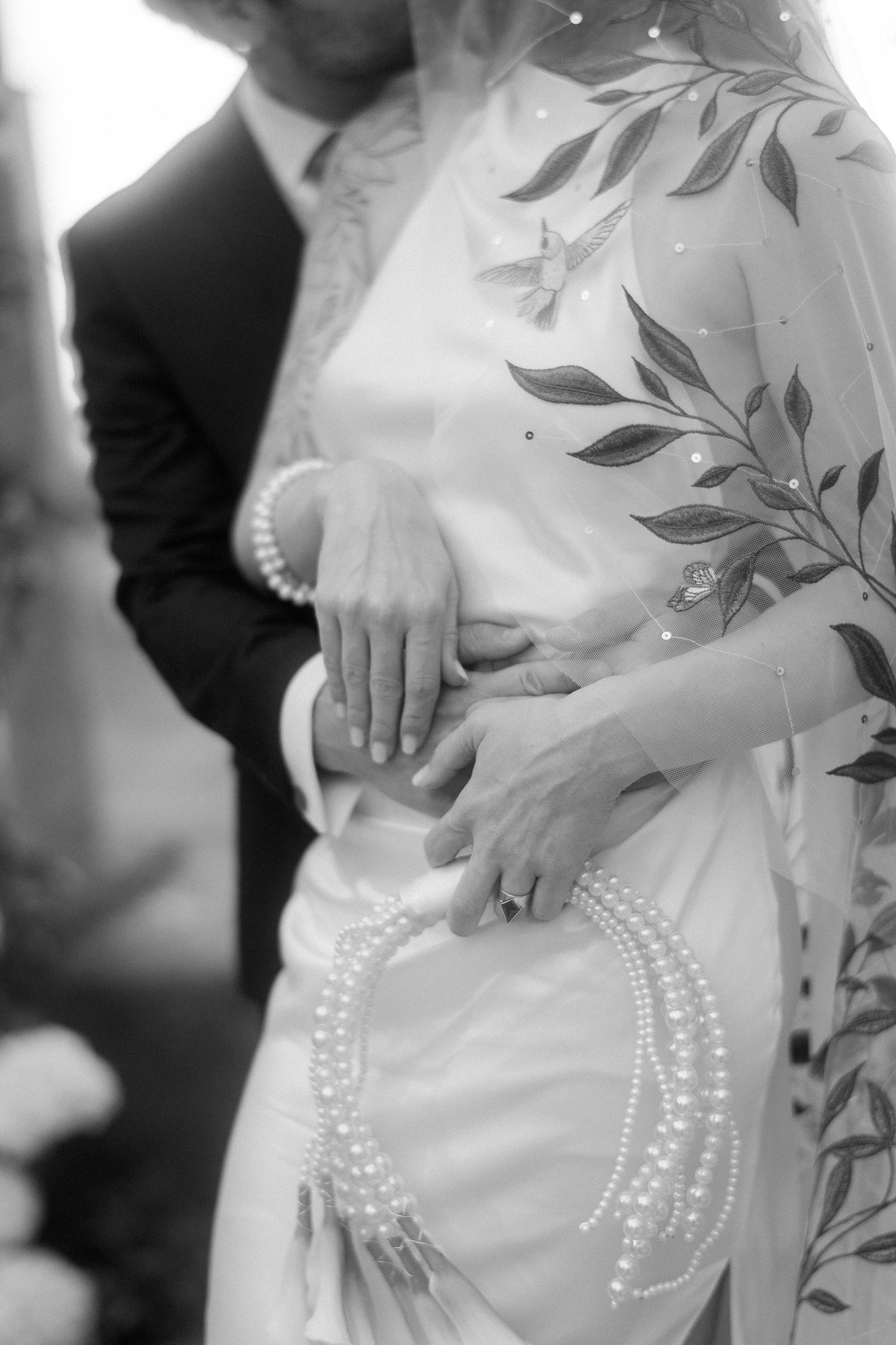 Black and white maternity photo series showing pregnant belly with pearl necklace draped across in artistic poses.