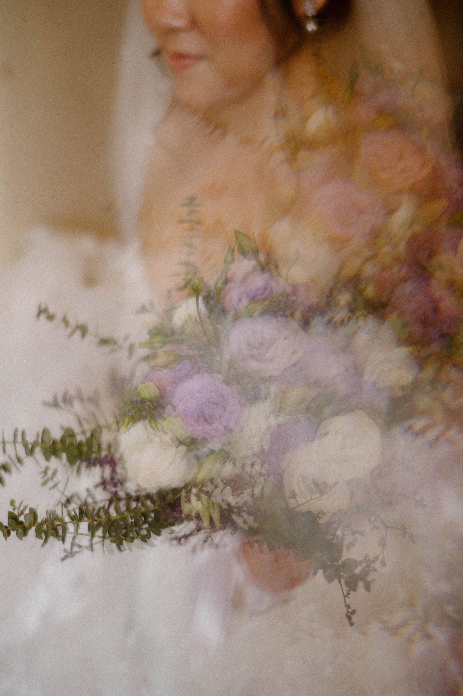 A dreamy soft-focus wedding bouquet features lavender and white roses with delicate greenery in a romantic style.