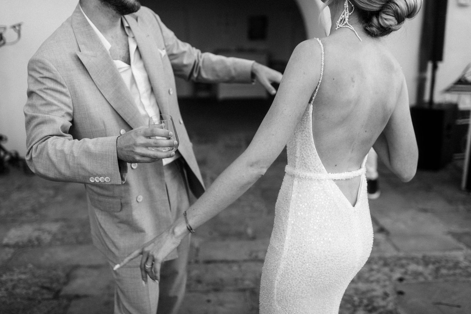 Black and white photo showing a person in a light colored suit standing next to someone wearing a fitted white dress.
