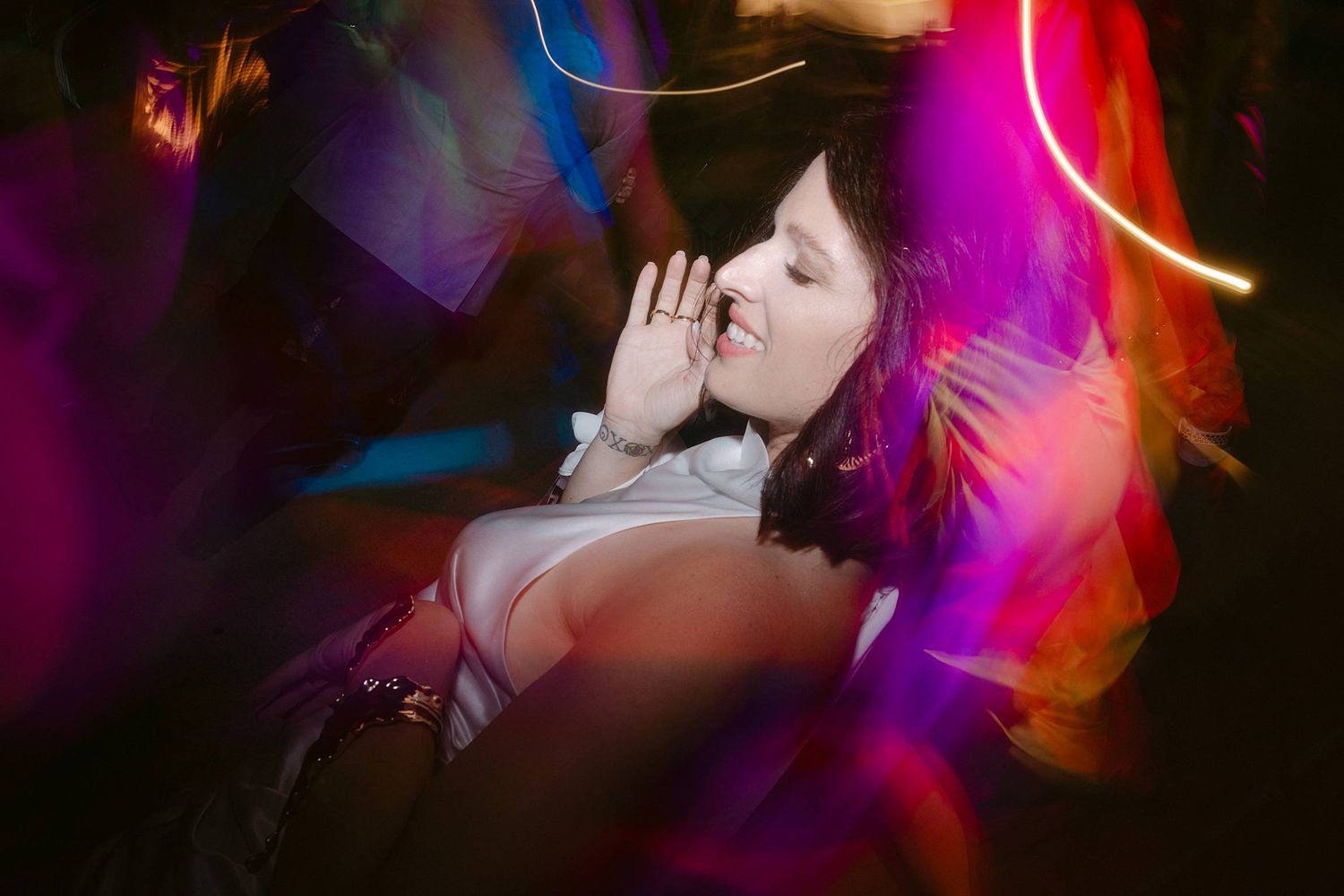 Artistic portrait with vibrant pink and blue light trails creating a dreamy neon atmosphere in darkness.