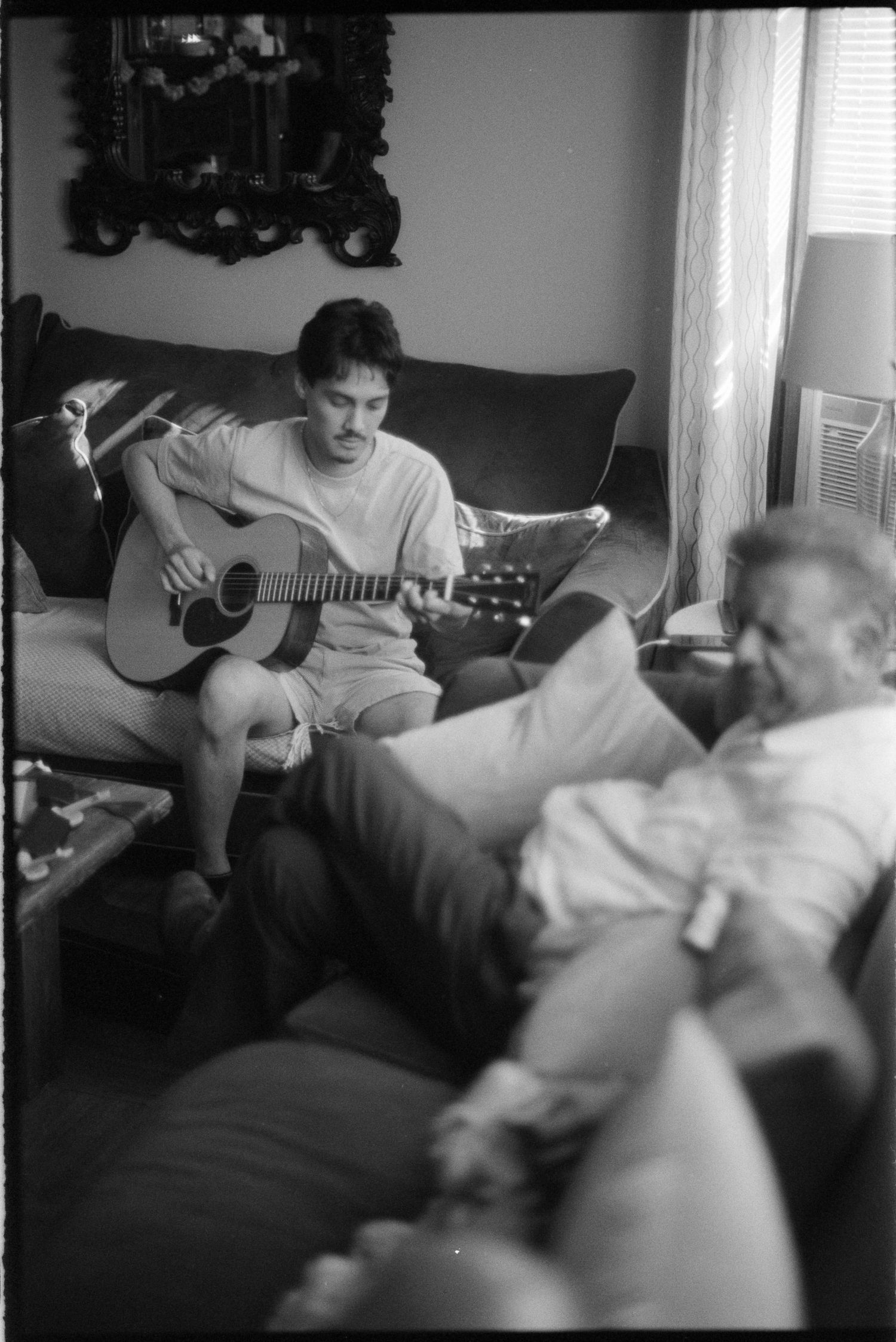 Black and white photo sequence showing someone playing acoustic guitar on a couch with a dog resting nearby.