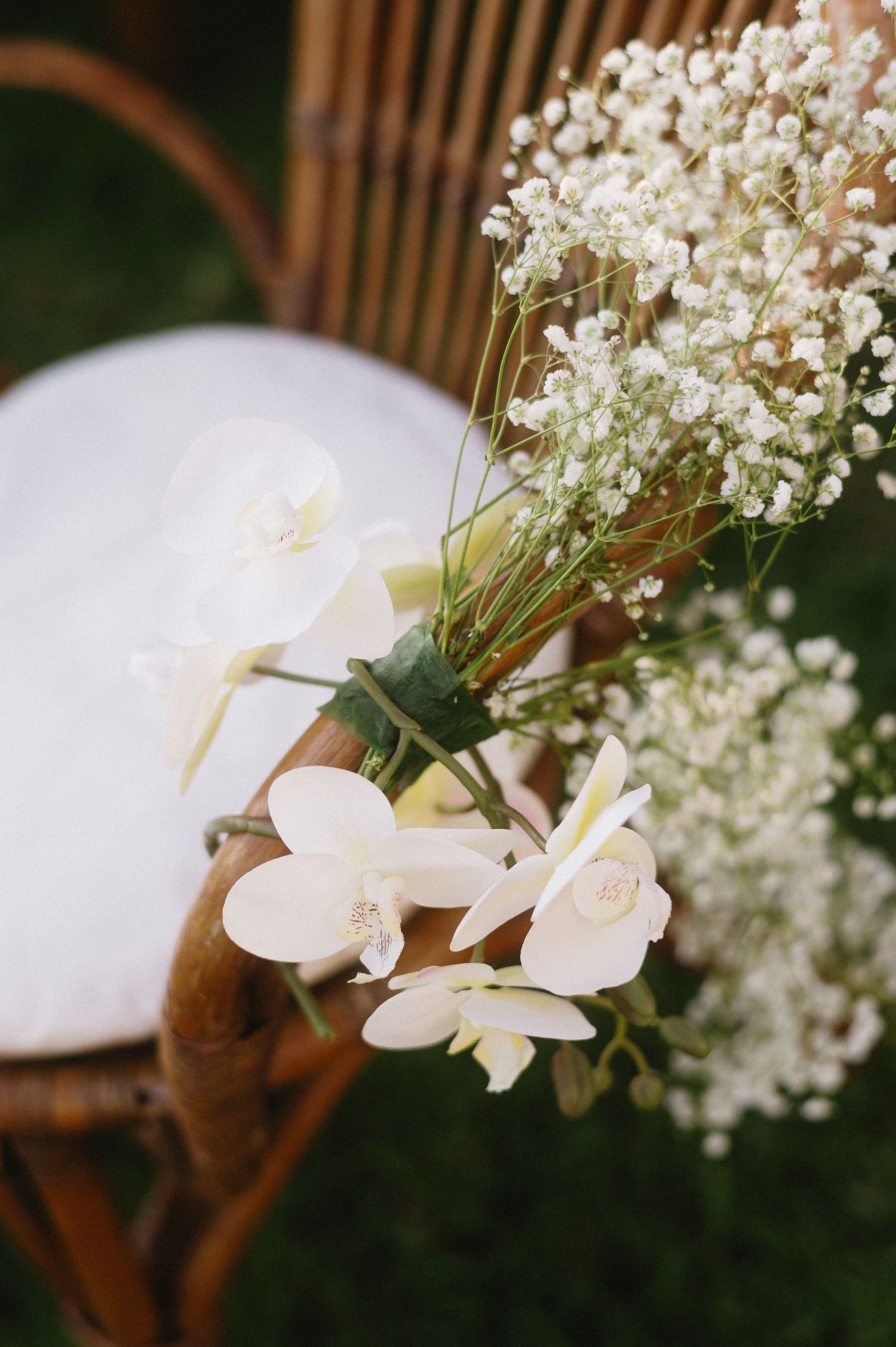 Delicate white orchids and baby's breath flowers arranged in a romantic wedding centerpiece against a wooden backdrop.