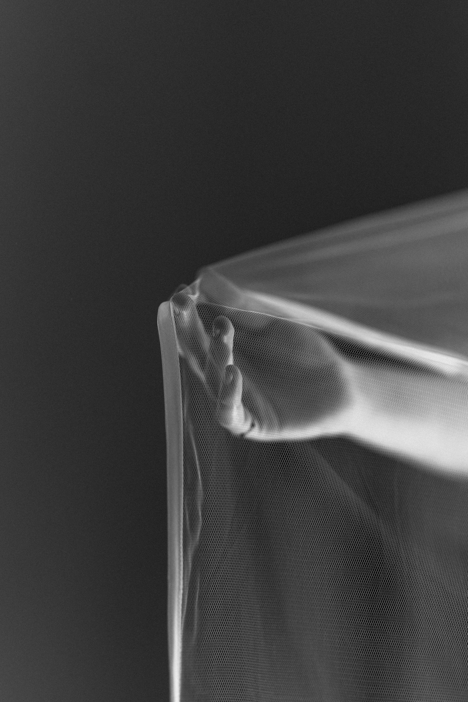 Black and white photograph showing wisps of smoke or vapor trailing across a minimalist composition.