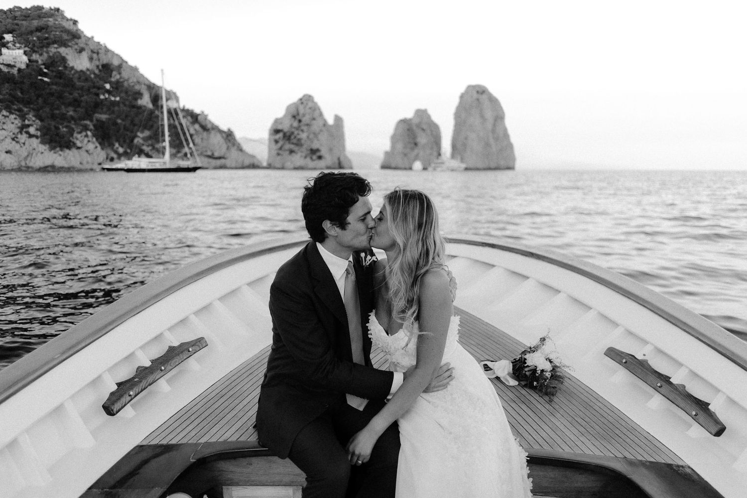 A romantic boat ride through the famous Faraglioni rock formations off the coast of Capri, Italy on a sunny day.