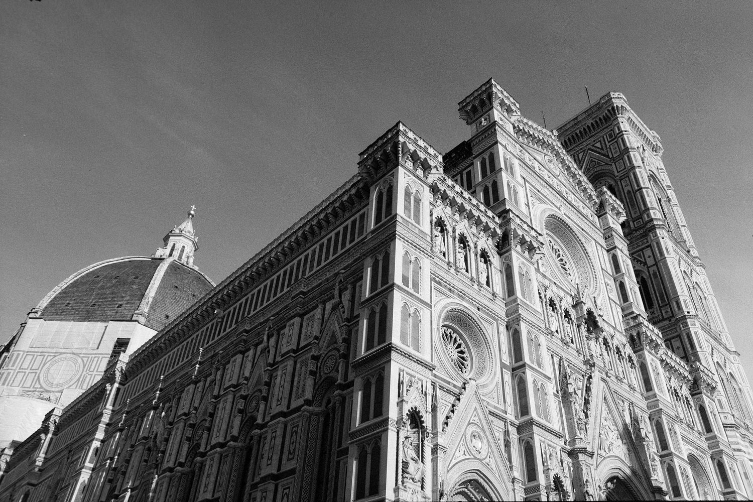 Historic cathedral facade with ornate Gothic architecture and decorative details photographed in black and white.
