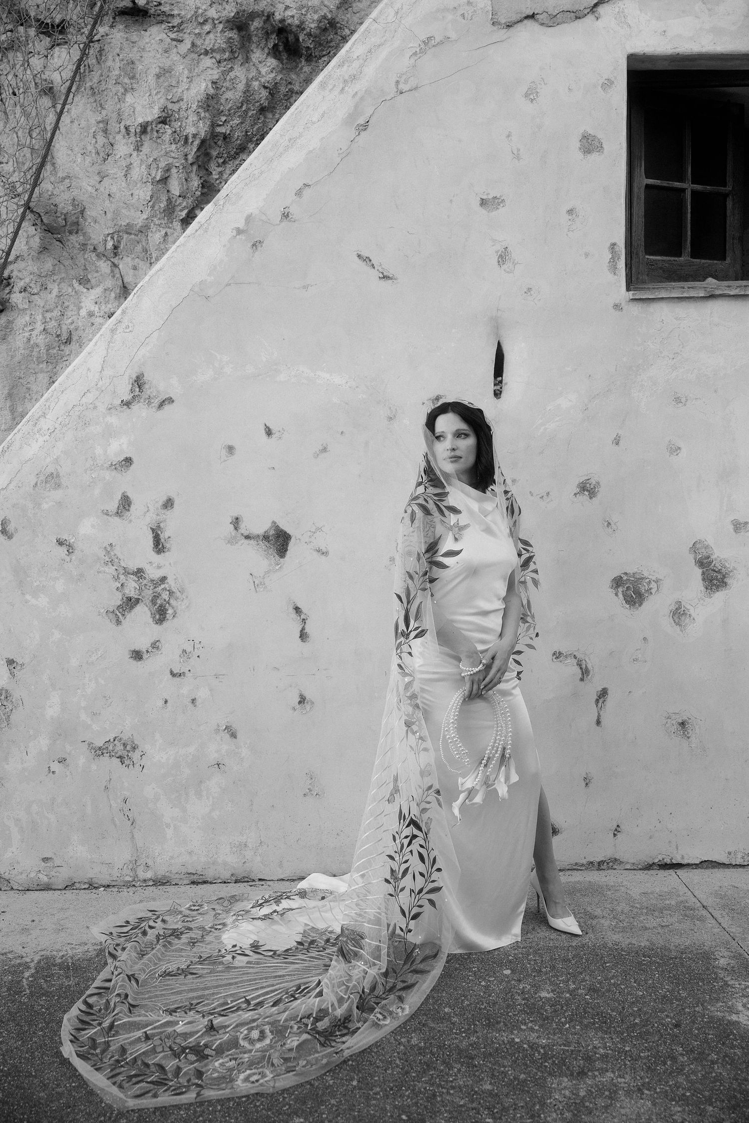 A black and white photo series showing a woman in a dress against a textured wall with flowing fabric movement.