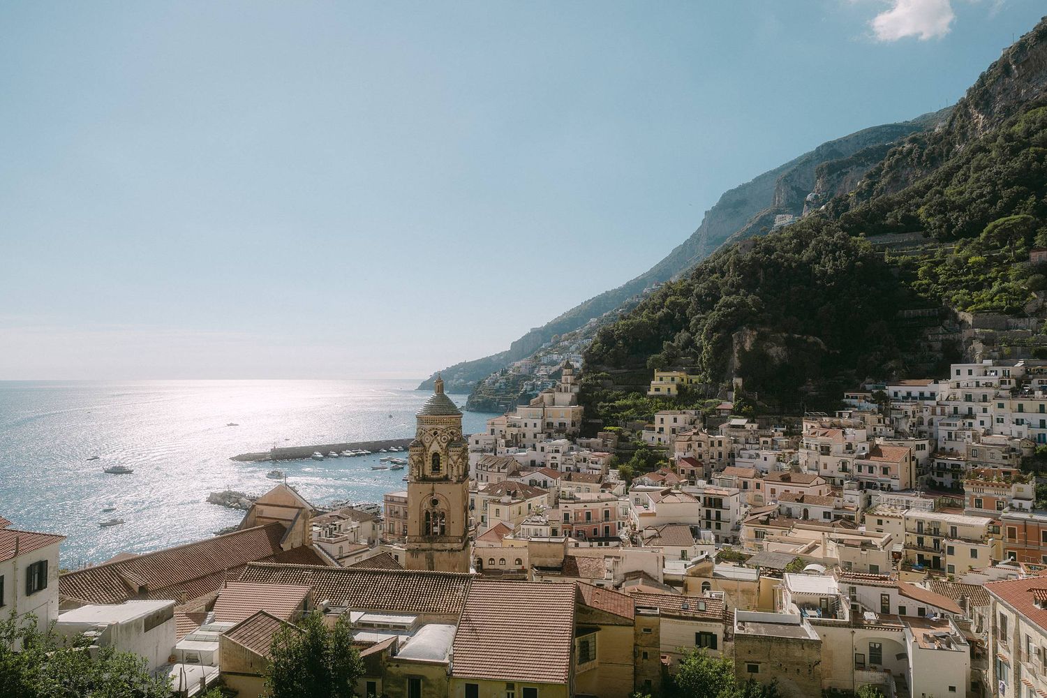 Scenic view of Positano coastal town in Italy with Mediterranean Sea, church dome and hillside buildings at sunset.