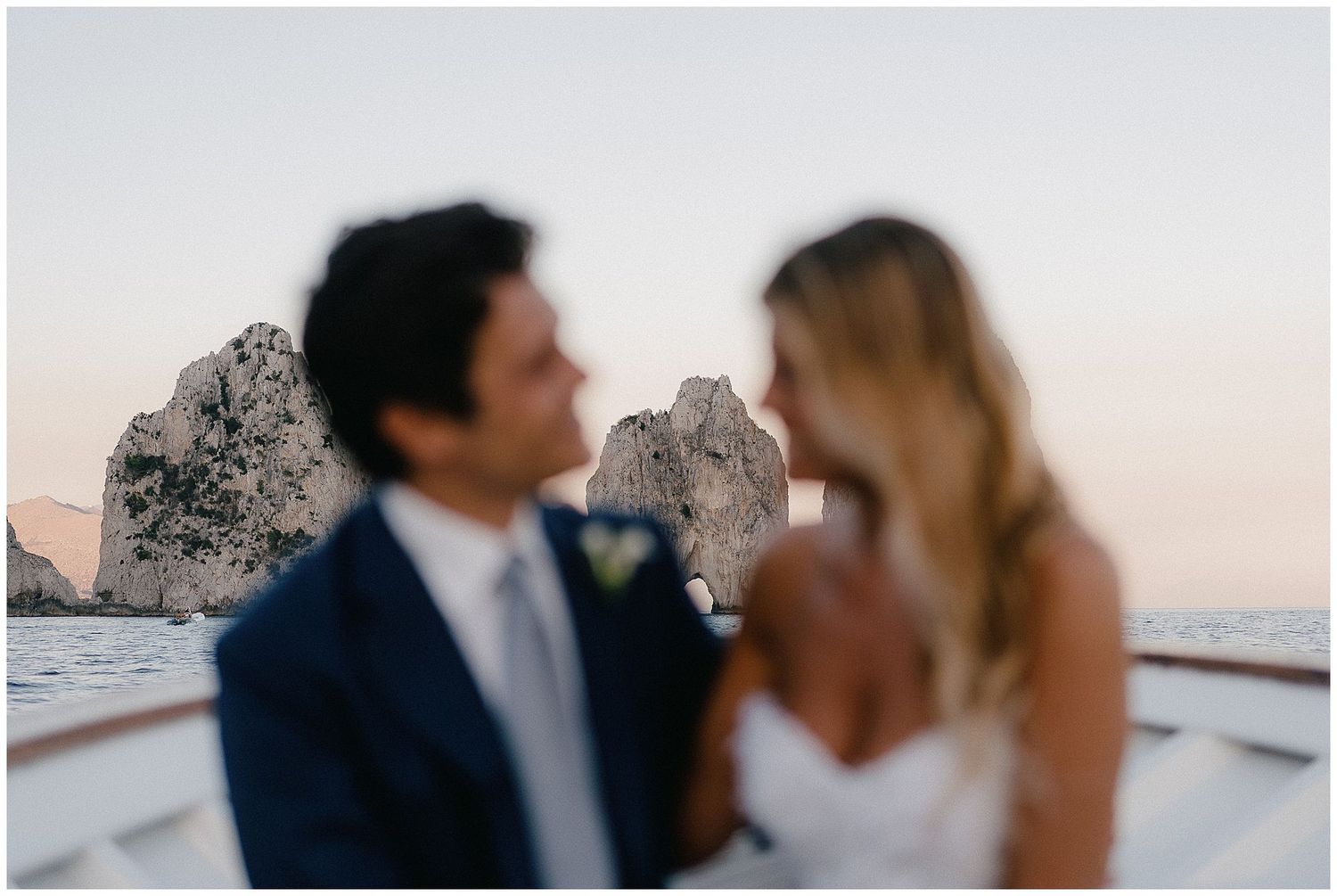 A couple poses together for a romantic wedding photo by the ocean cliffs at sunset.