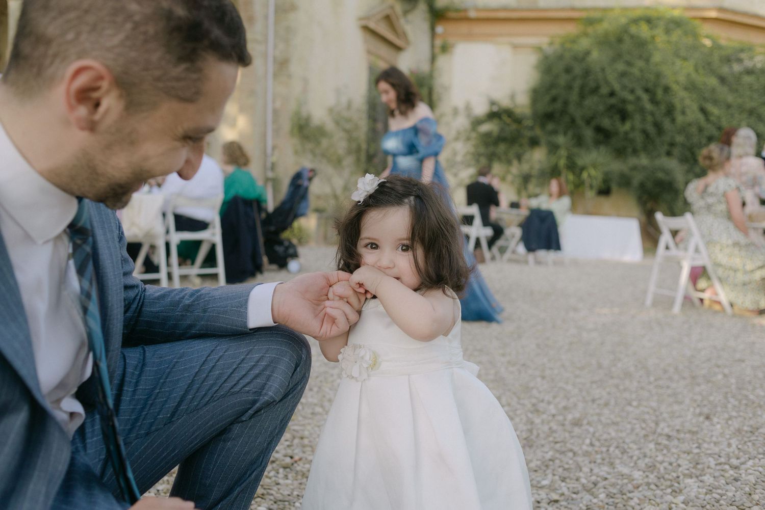 A couple shares an intimate moment during an outdoor wedding celebration on a gravel path.
