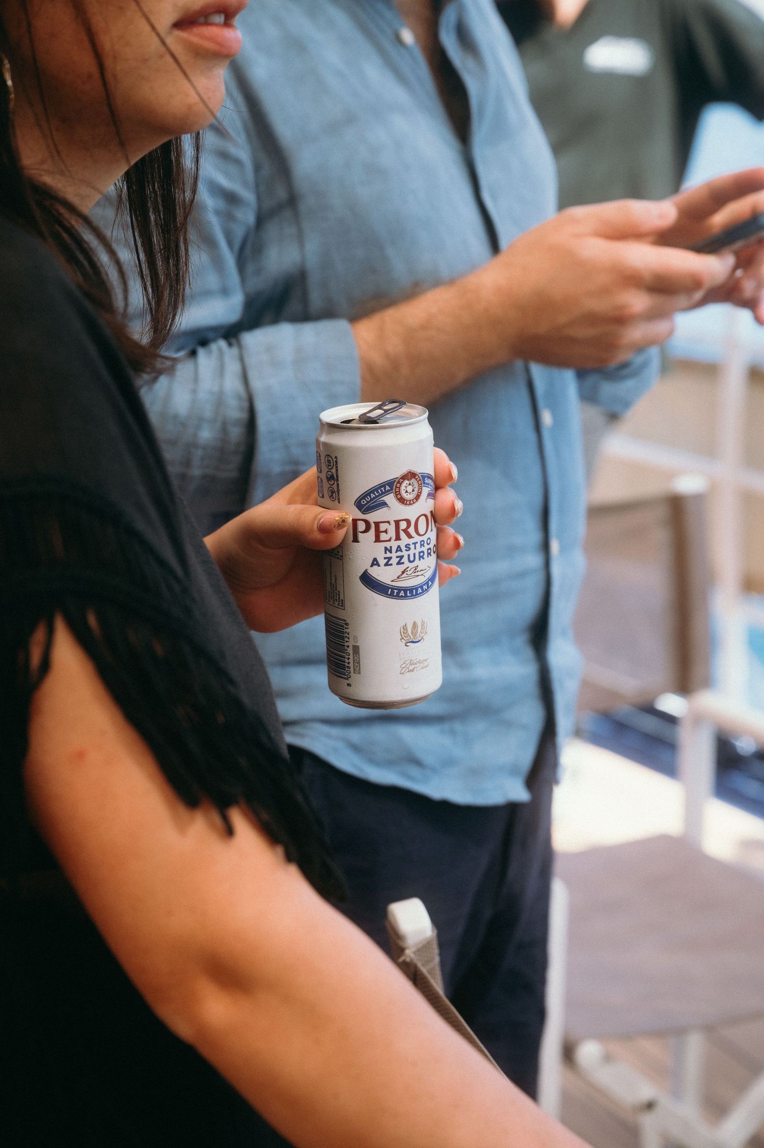Someone holding a Peroni beer mug while sitting at a table in casual attire.