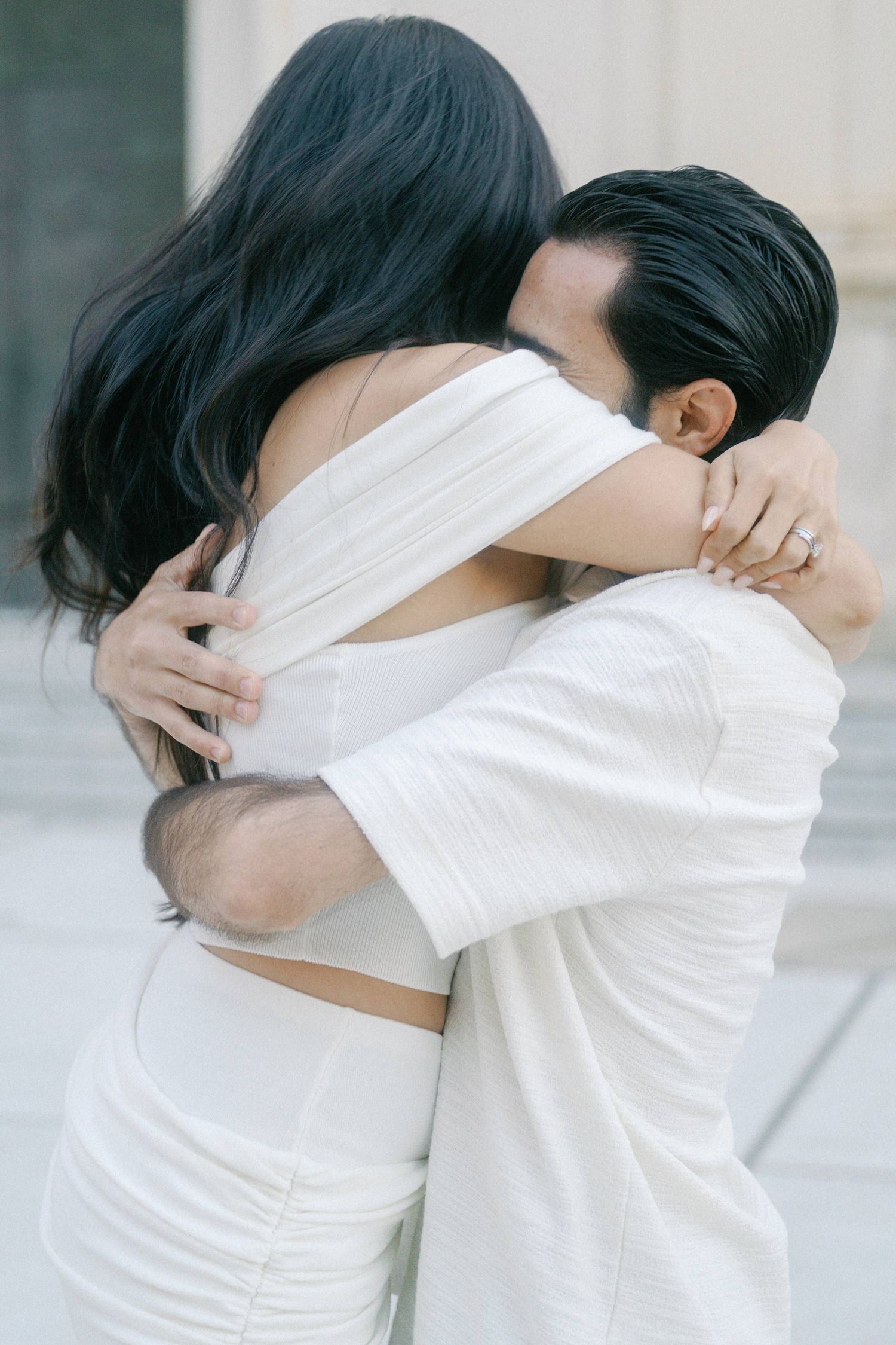 A tender embrace between two people wearing white clothing, sharing an intimate moment during a romantic photoshoot.