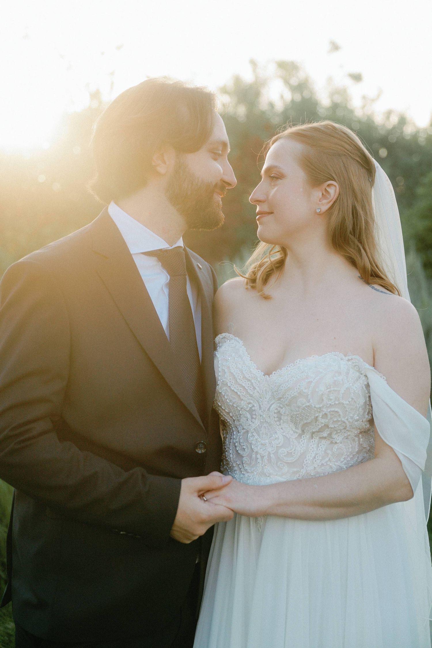 A romantic sunset wedding portrait showing a couple in wedding attire sharing an intimate moment outdoors.