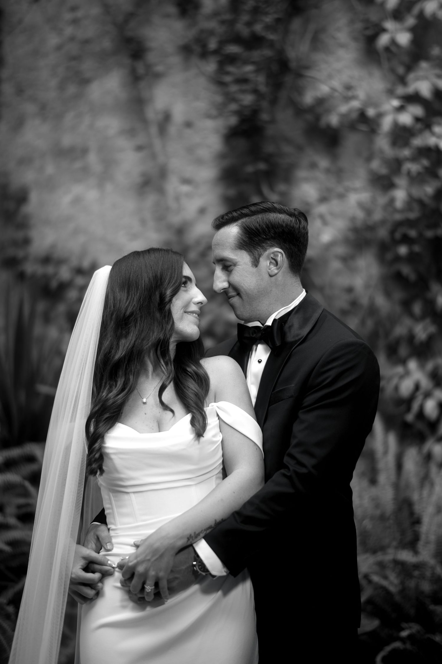 A romantic black and white photo sequence of newlyweds sharing intimate moments and kisses in a garden setting.