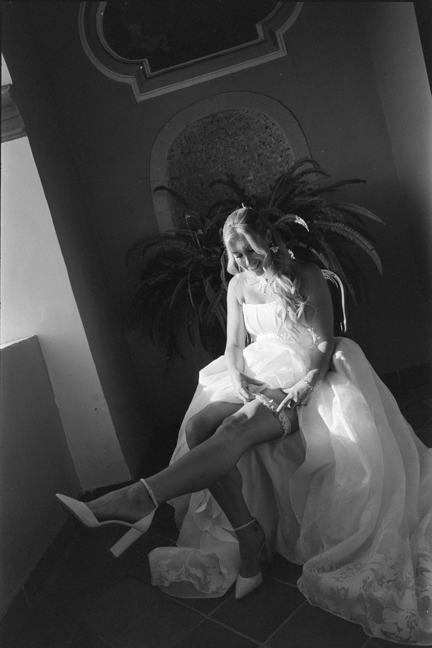 A sequence of black and white photos showing a person in a white dress moving through a dark hallway.