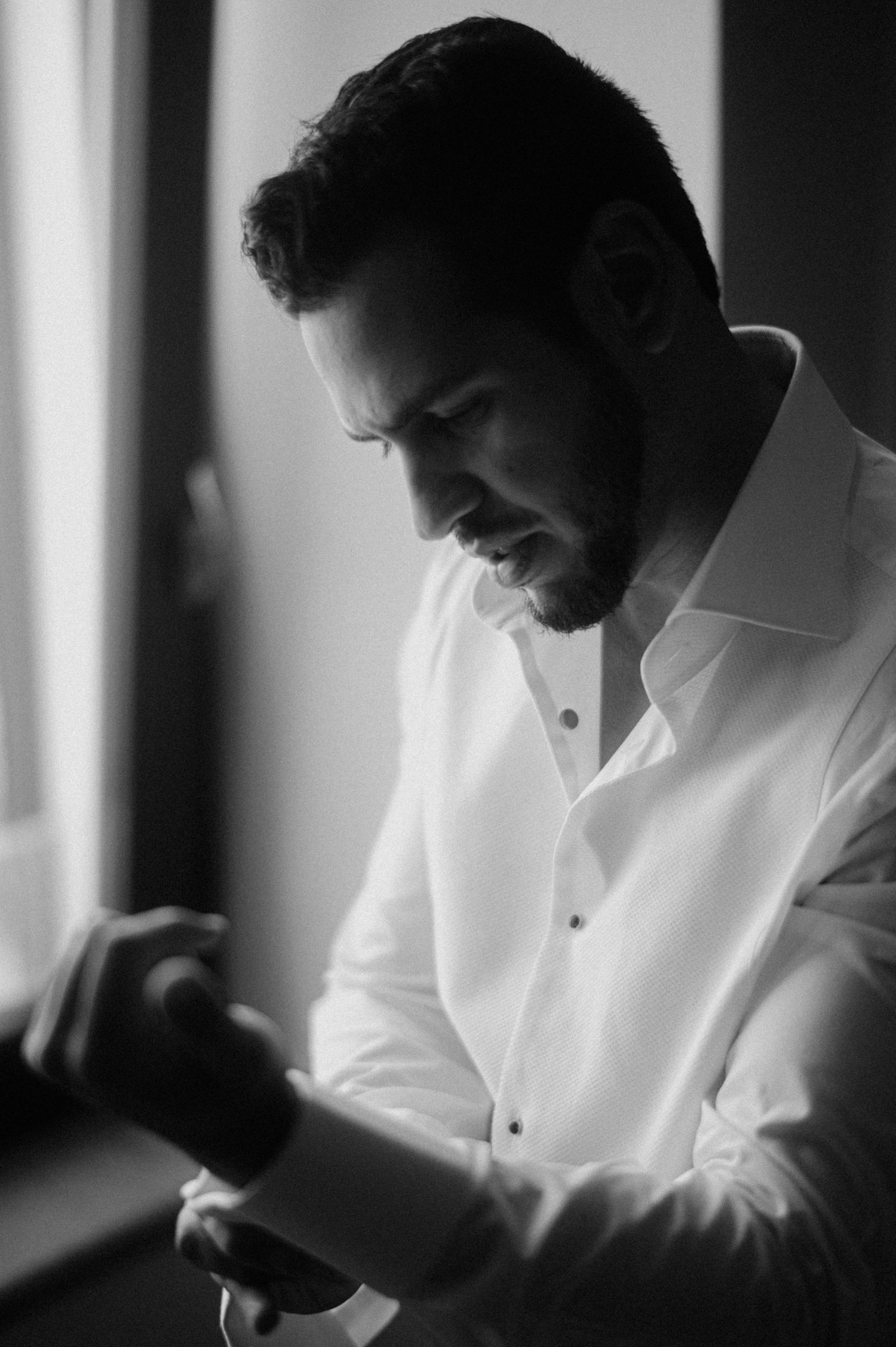 A black and white photo series showing a person in a white dress shirt looking down in dramatic lighting.