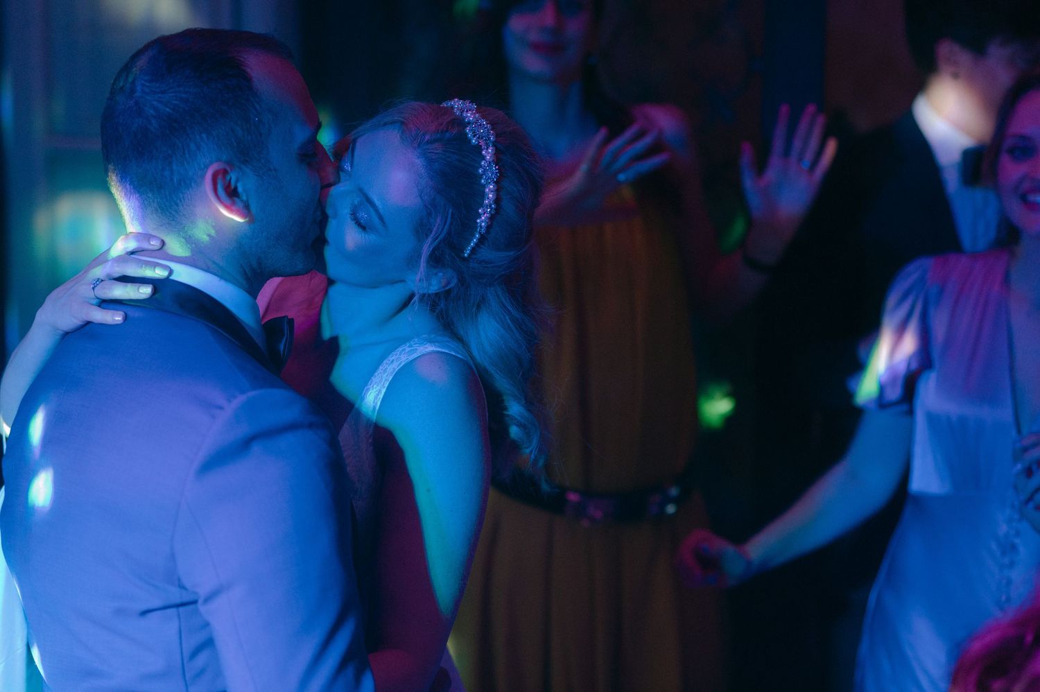 People dancing and enjoying themselves at a nightclub with blue lighting and a crowded dance floor.