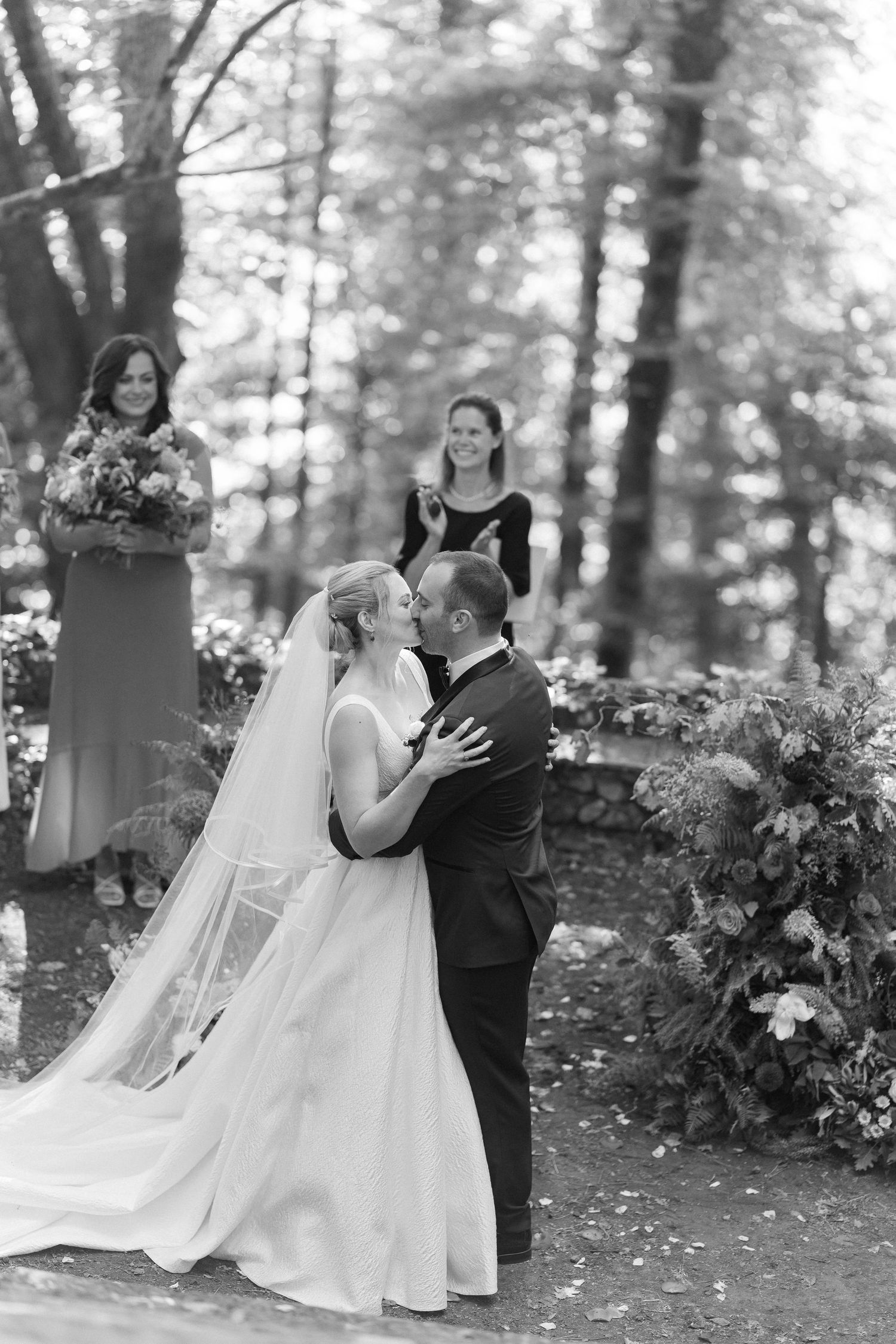 Black and white wedding photos show romantic moments between a couple dancing and embracing in a wooded outdoor setting.