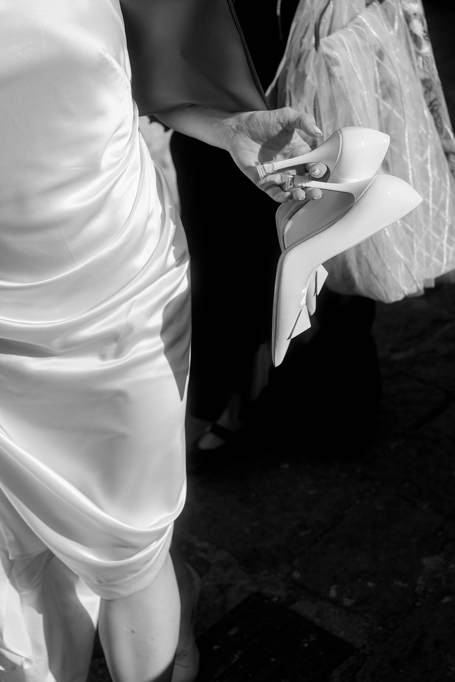A series of black and white photos showing close-up details of a white wedding dress and veil in dramatic lighting.