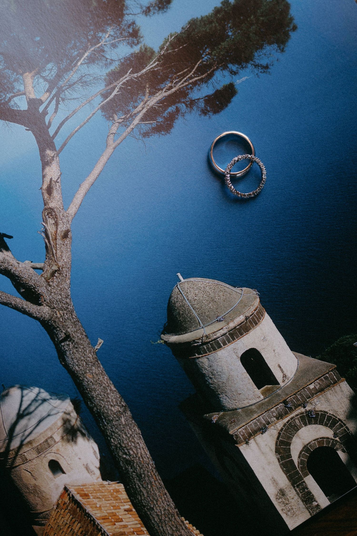 A series of artistic photos showing a white stone lighthouse structure against a deep blue sky with pine tree branches.