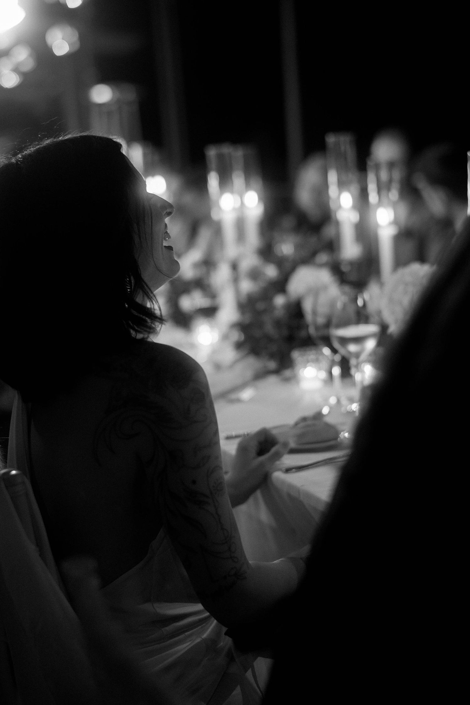 Black and white silhouettes of guests enjoying a romantic candlelit dinner reception in an elegant setting.