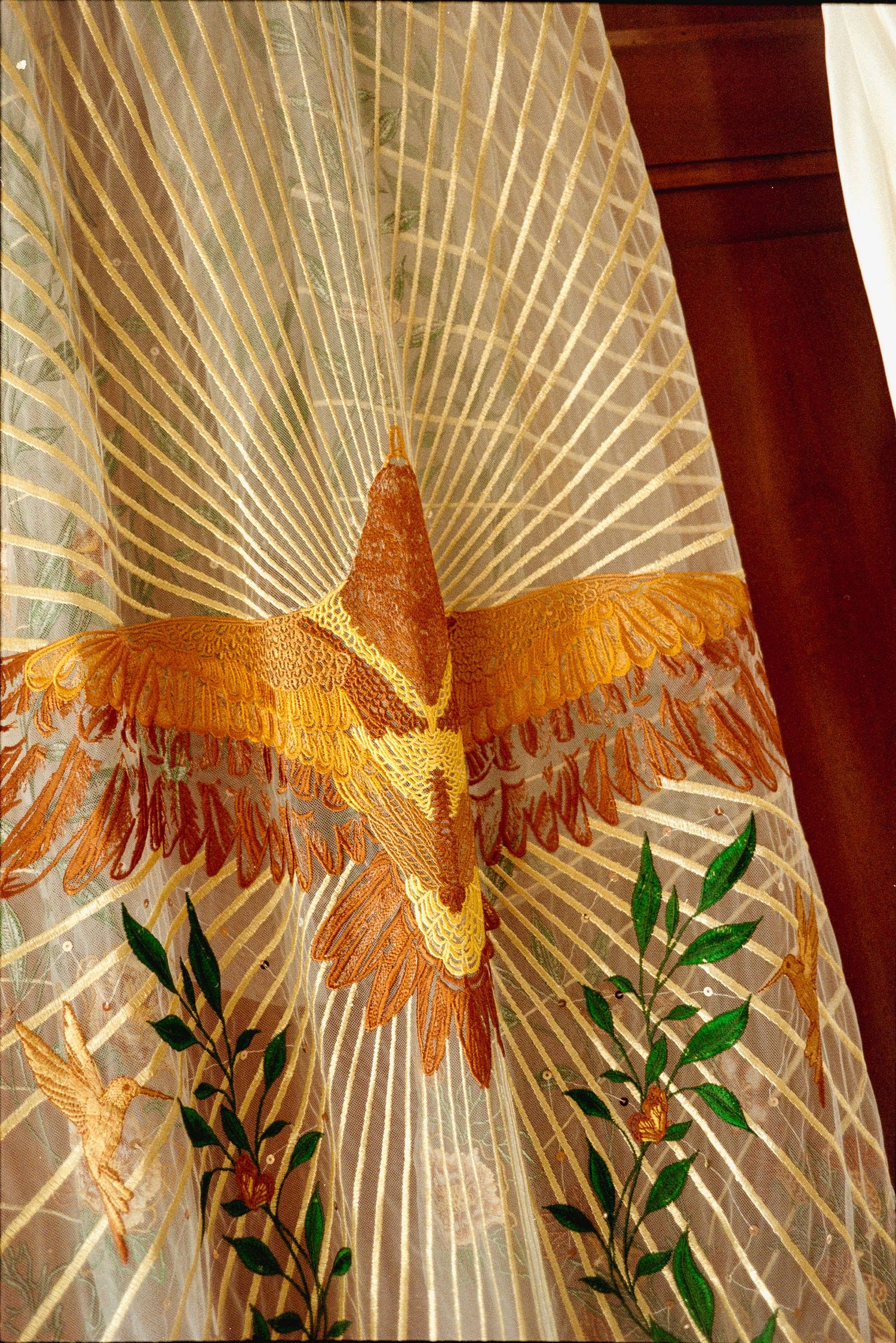 Decorative golden eagle sculpture mounted on wall with radiating lines and green foliage accents.